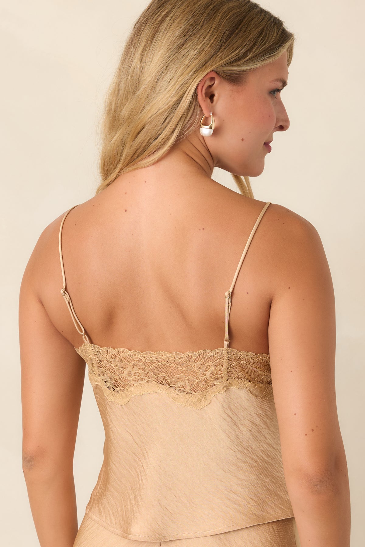 Rear view of the tan top featuring delicate lace trim, adjustable straps, and a relaxed draped shape.