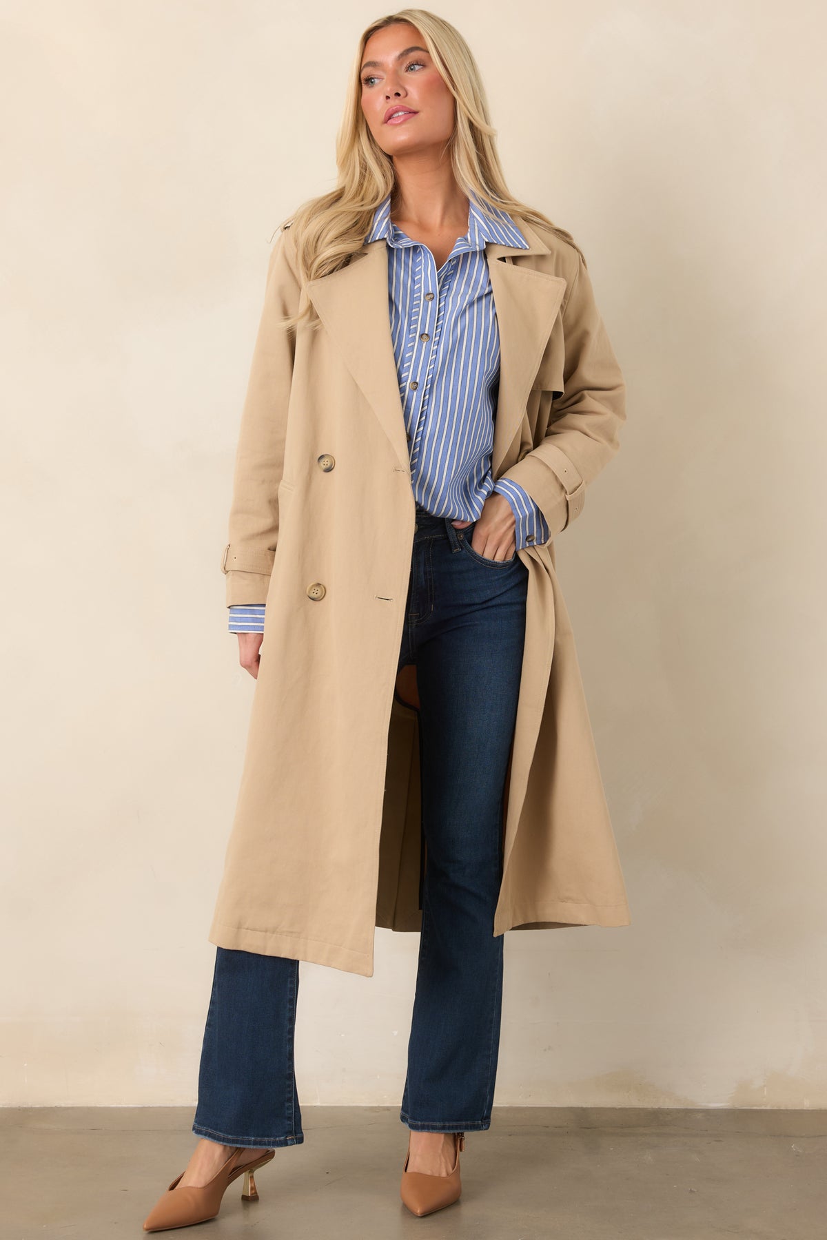 Tan trench coat detail emphasizing the adjustable buckled cuff and neatly tailored long sleeve.