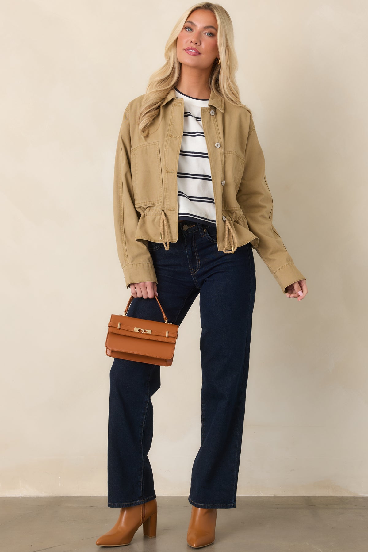 Tan utility jacket with a relaxed silhouette, collared neckline, long sleeves, and large patch pockets.