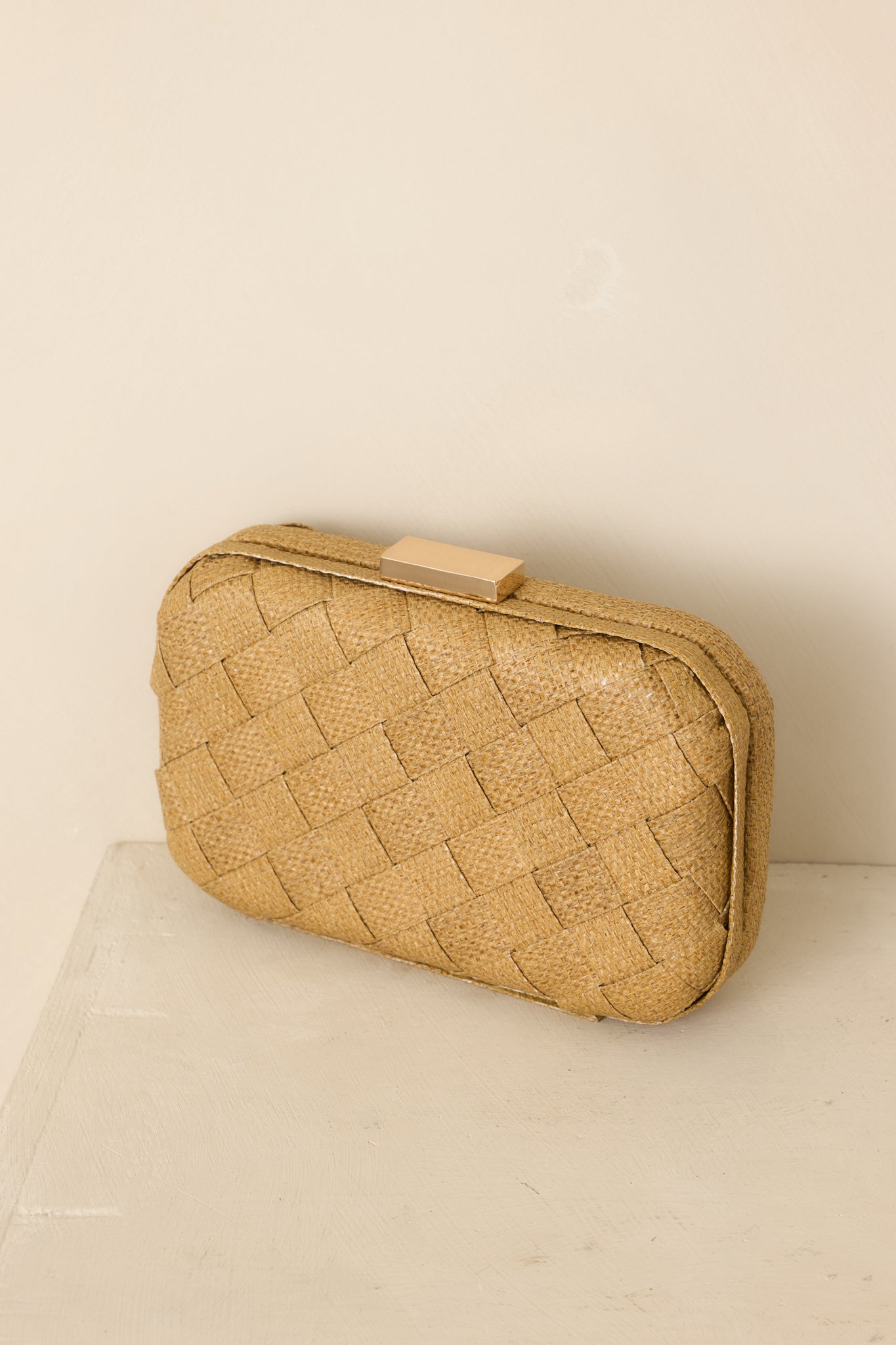 Tan woven clutch featuring a sleek structured shape and polished gold-tone clasp for an elegant finishing touch.