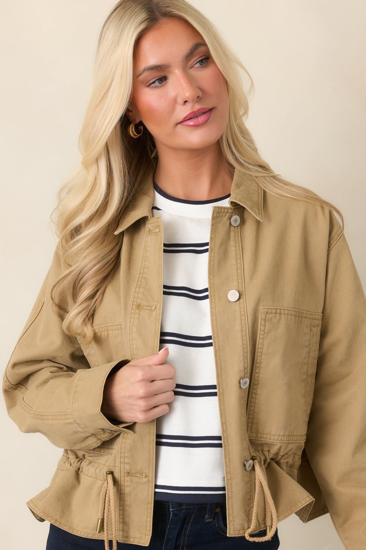 Tan woven jacket featuring long sleeves with button cuffs and a relaxed silhouette.