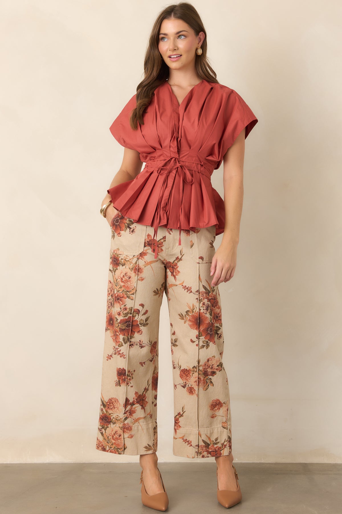 Taupe cotton pants featuring a rust floral print, high-rise waist, front patch pockets, and cropped wide-leg silhouette.