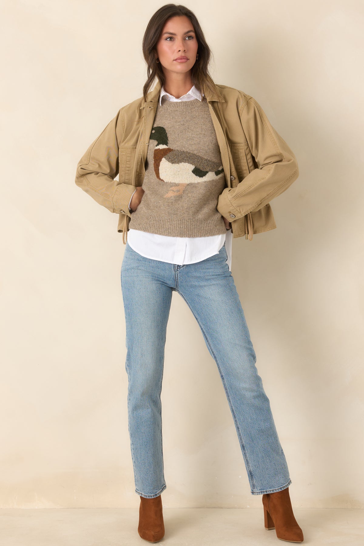 Relaxed taupe sweater features a classic crew neckline, long sleeves, and a countryside-inspired duck motif.
