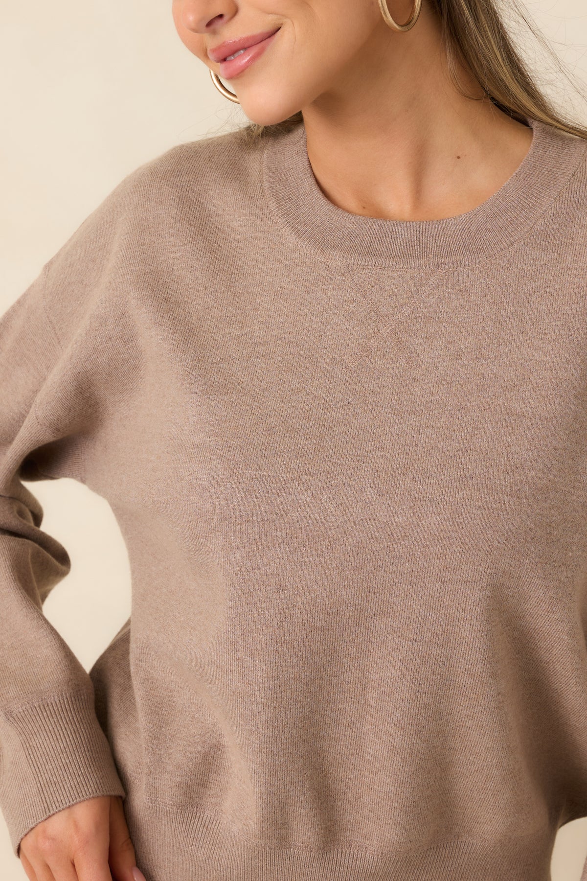 Close detail of the taupe sweater’s heathered knit texture and ribbed crew neckline.