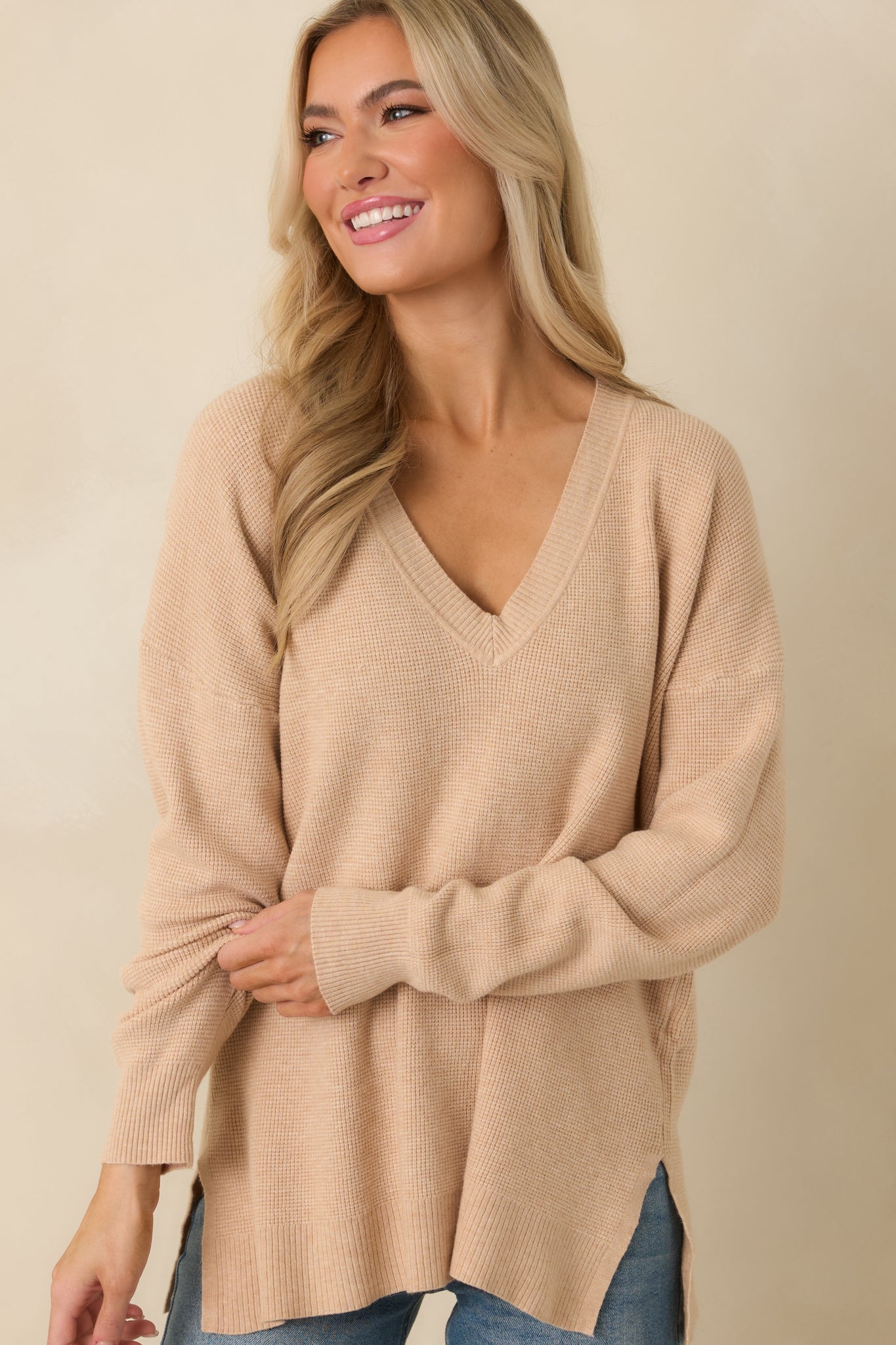 Detail of taupe V-neck sweater with ribbed sleeve cuffs and lightweight, relaxed fit.