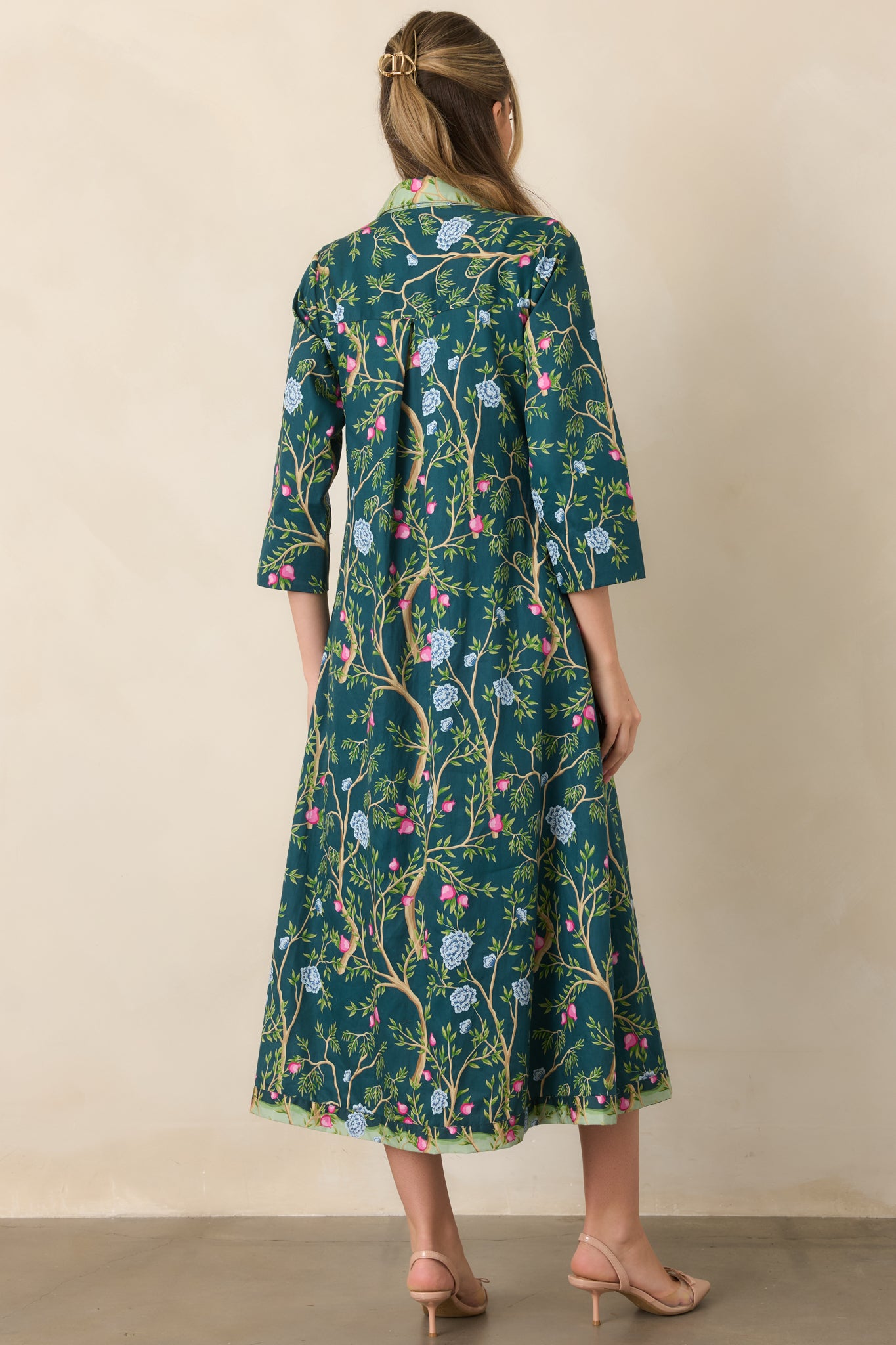Rear view of the deep teal cotton dress showcasing the winding botanical print, three-quarter sleeves, collared neckline, and softly flowing silhouette.