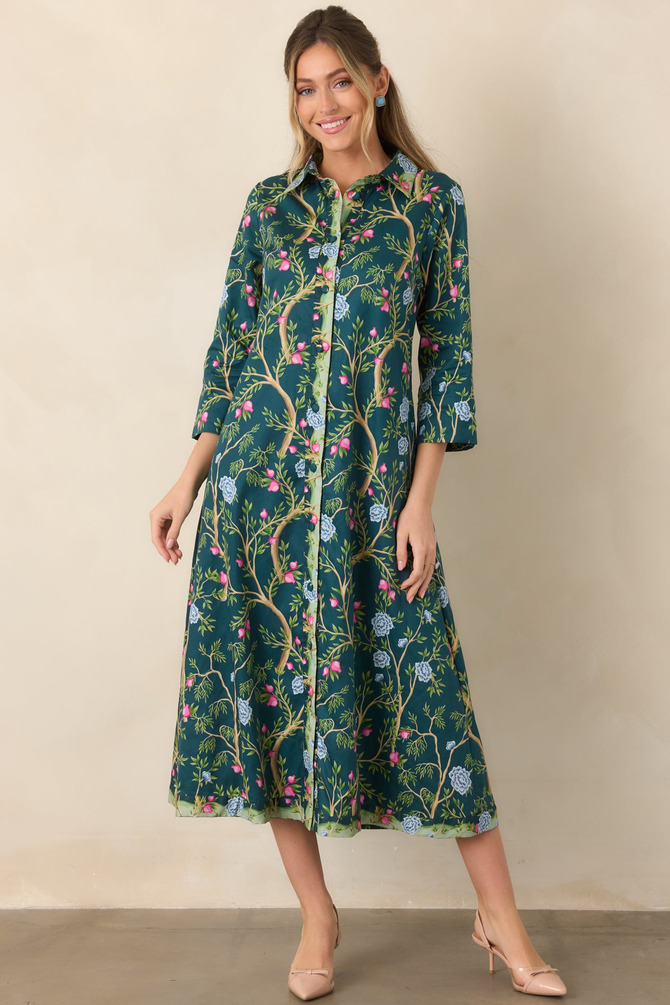 Teal botanical midi dress designed with delicate pink buds, fresh green foliage, blue floral blooms, three-quarter sleeves, and a polished button-front bodice.