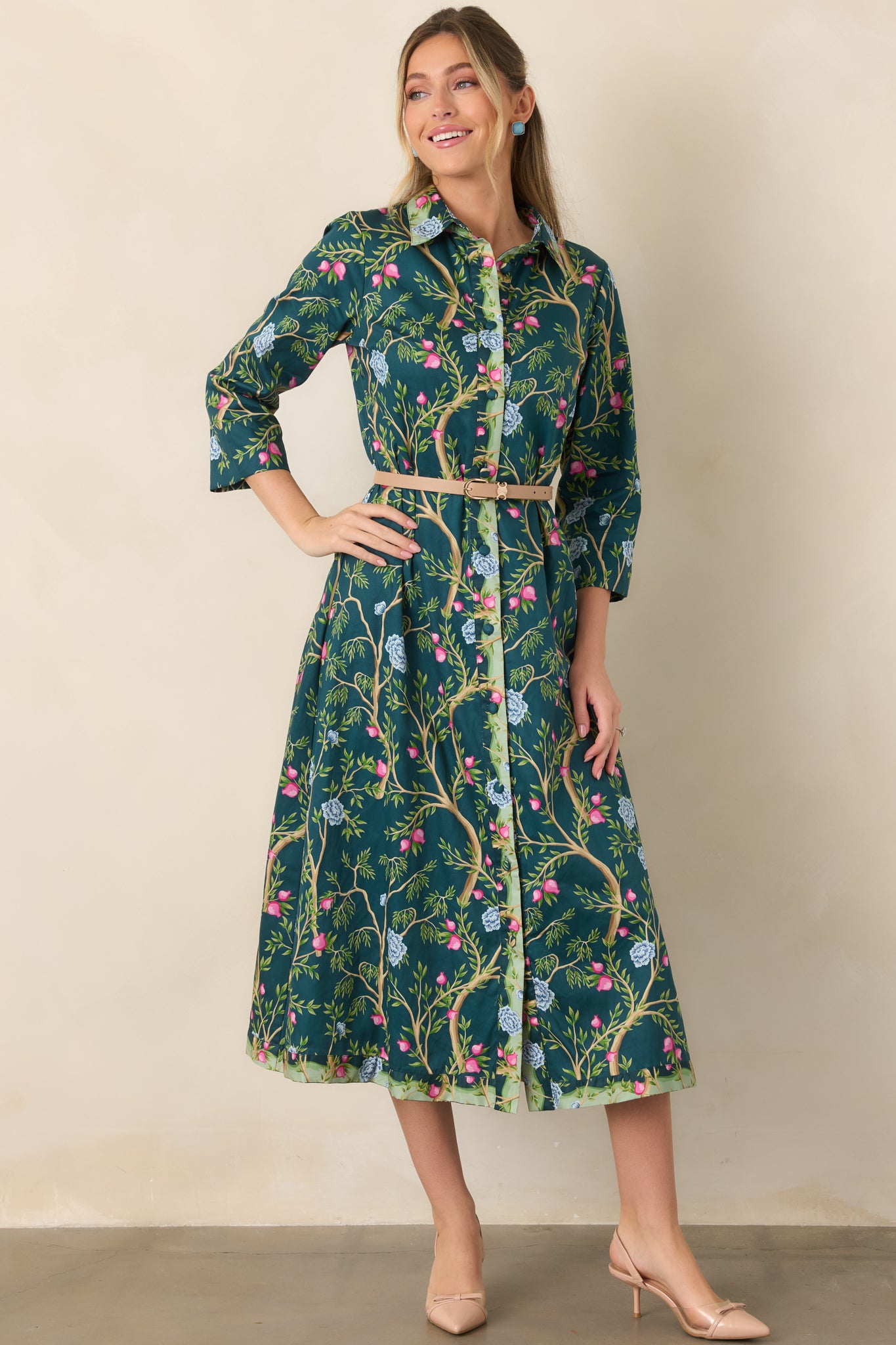 100% cotton dress showcasing a rich teal background, intricate botanical pattern, fabric-covered buttons, collared neckline, and softly flowing silhouette.