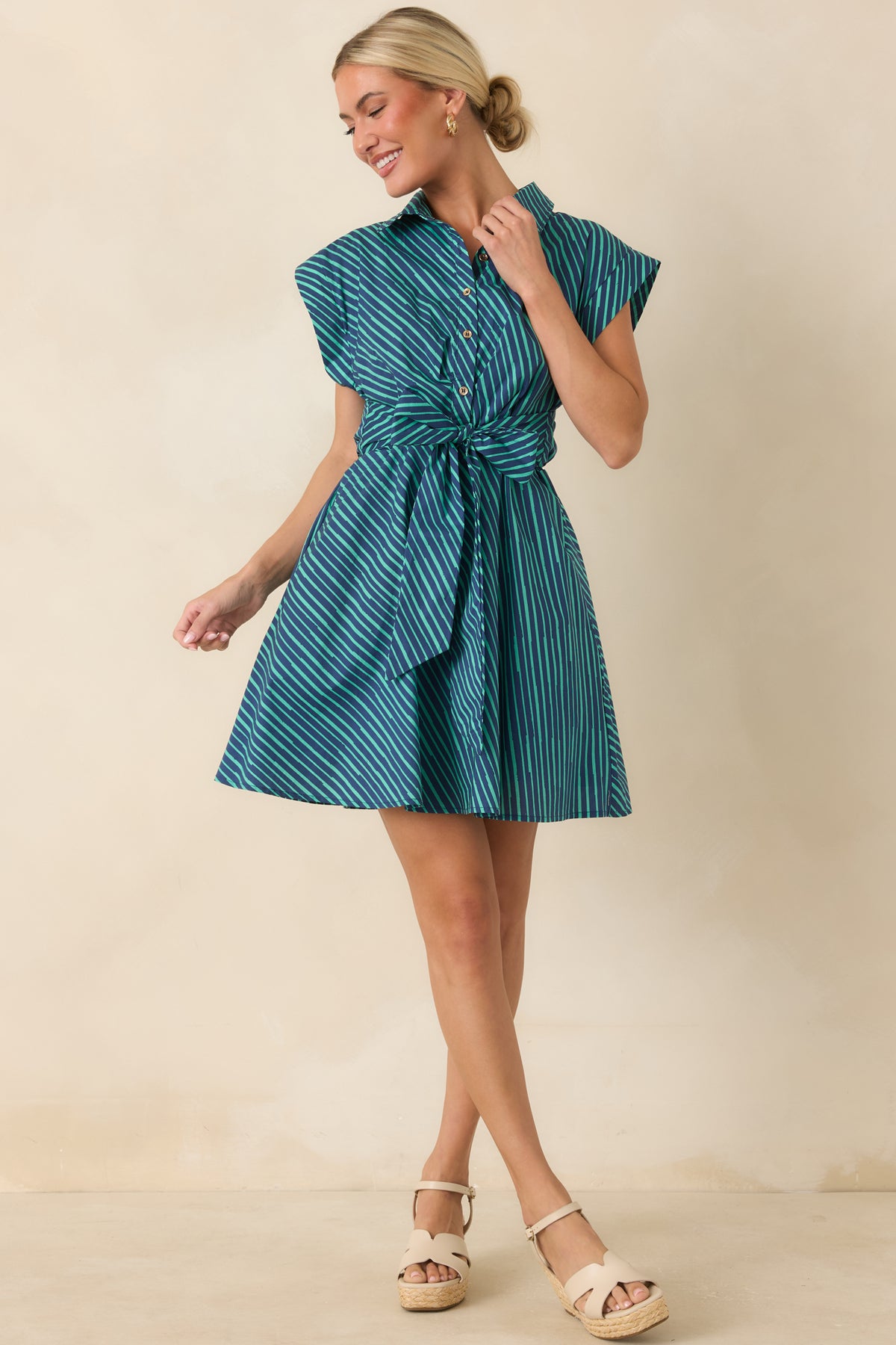 Playful shirtdress-style mini featuring a teal and navy pattern, collared neckline, and flattering waist tie.