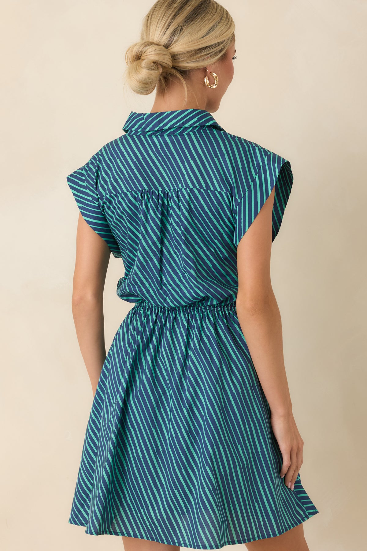 Back view of the teal and navy striped mini dress featuring cap sleeves, a flared skirt, and a clean patterned finish.