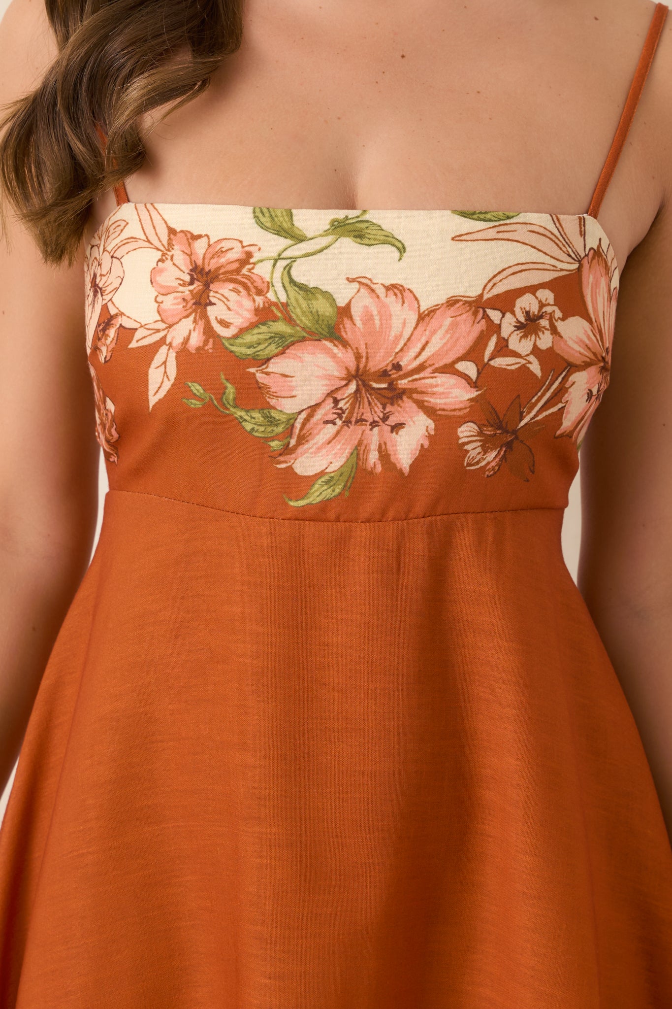 Close-up of the fitted bodice showcasing the large-scale ivory, blush, and green floral border print against terracotta.