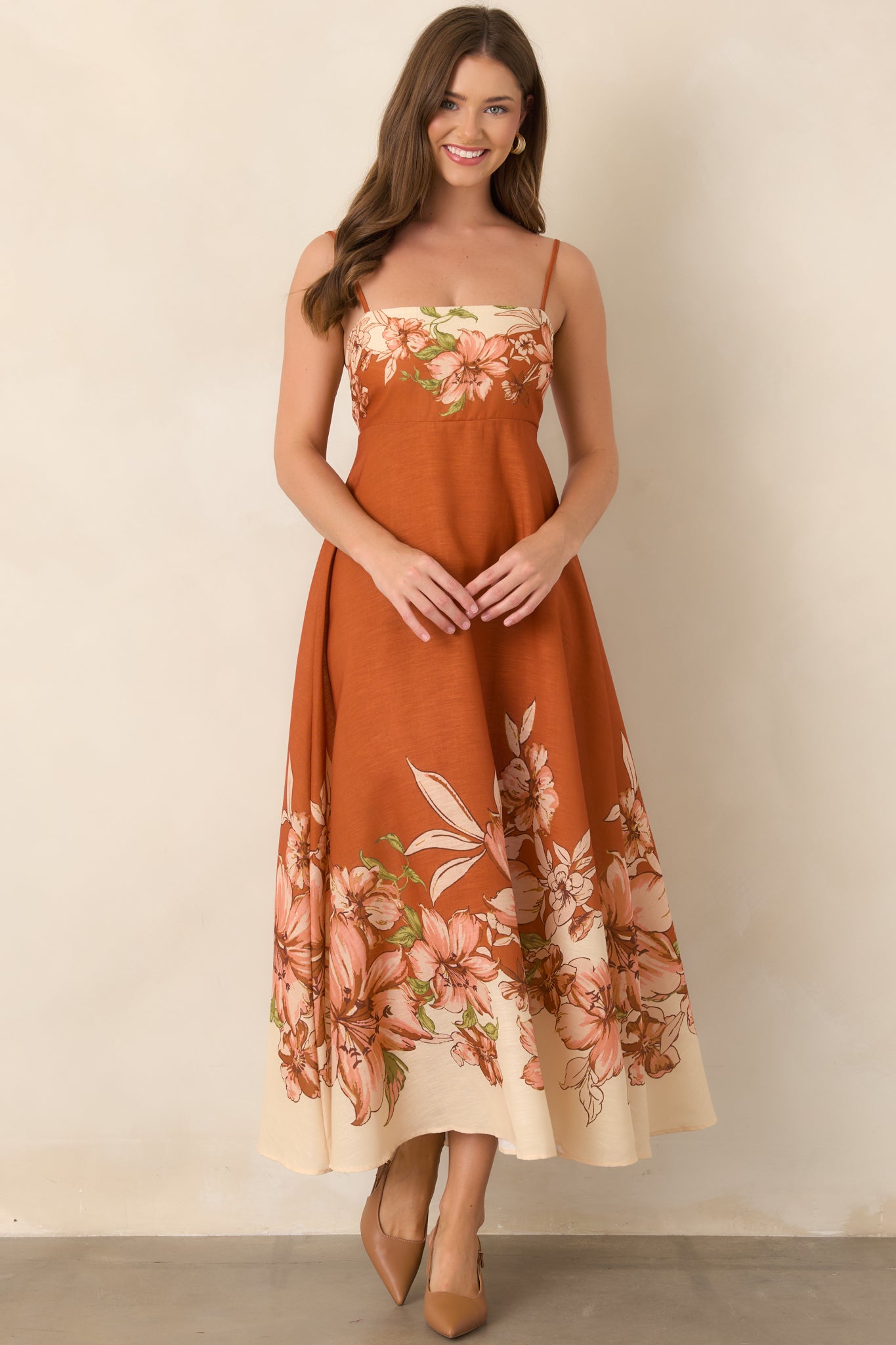 Terracotta dress highlighting its straight neckline and softly draped empire-waist silhouette with bold floral borders.