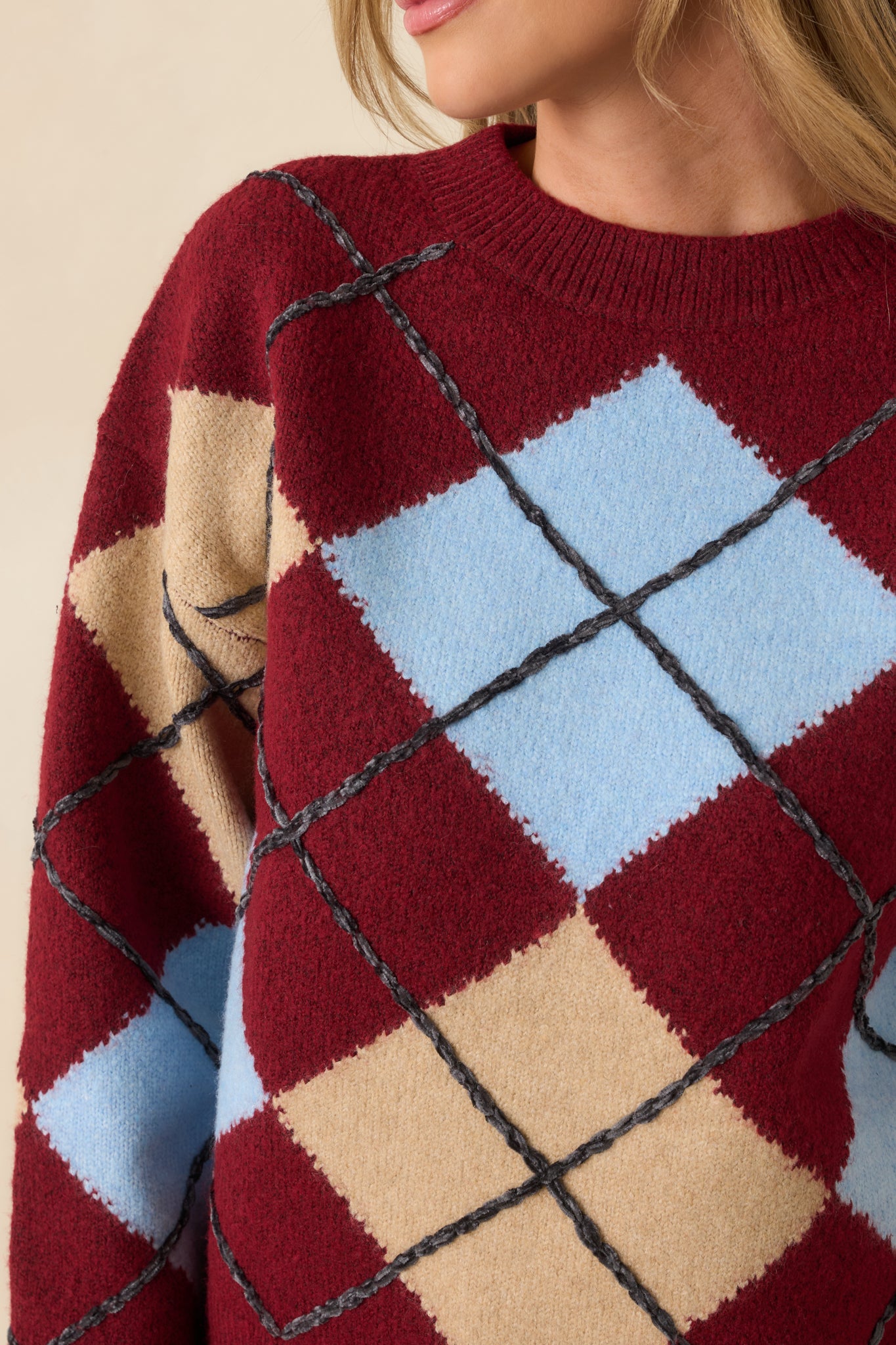 Texture-focused view of soft knit fabric and multicolor argyle pattern on sweater.