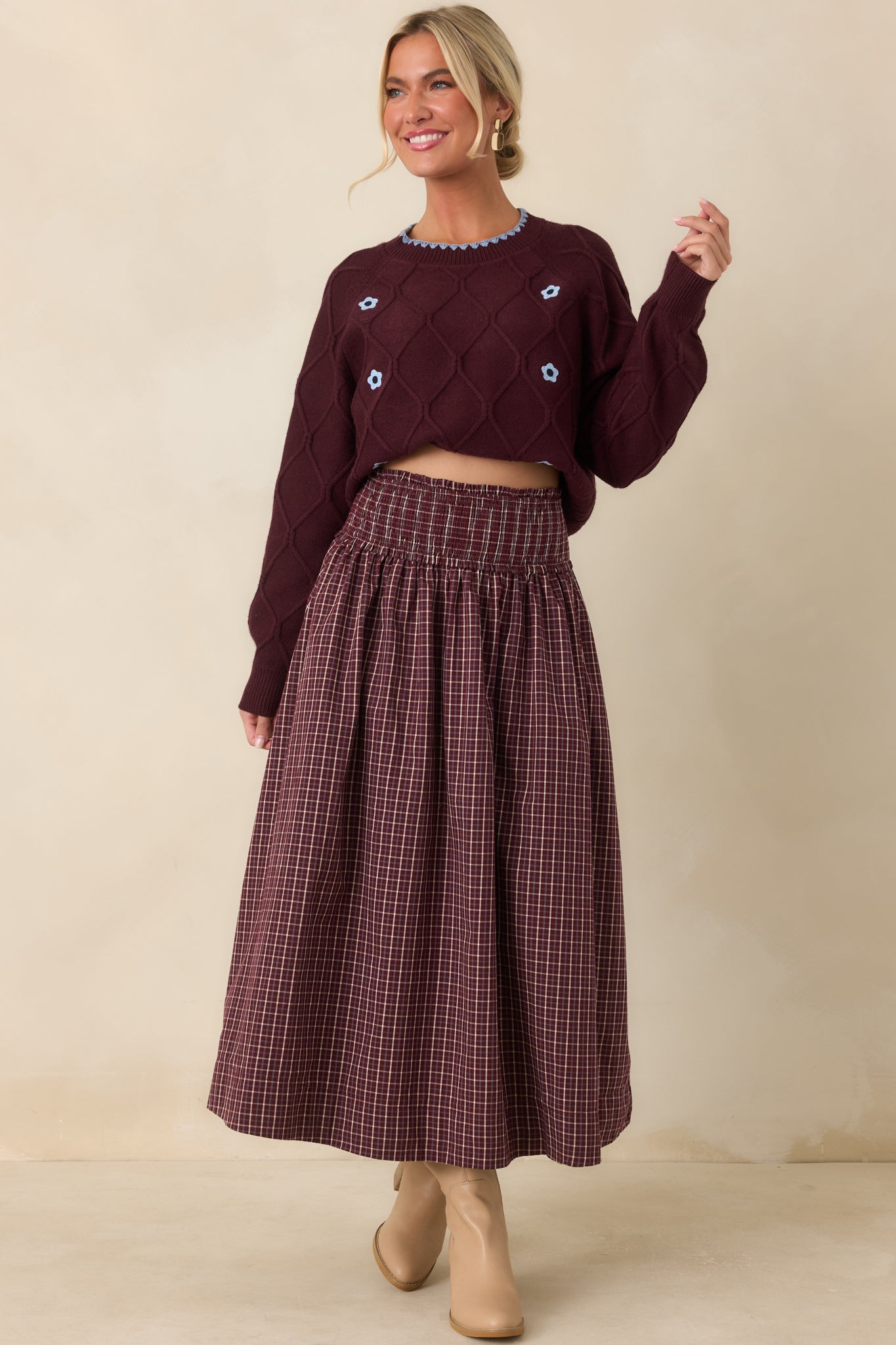 Textured burgundy sweater with a raised diamond-knit pattern, contrasting blue floral details, scalloped neckline trim, and ribbed edges.