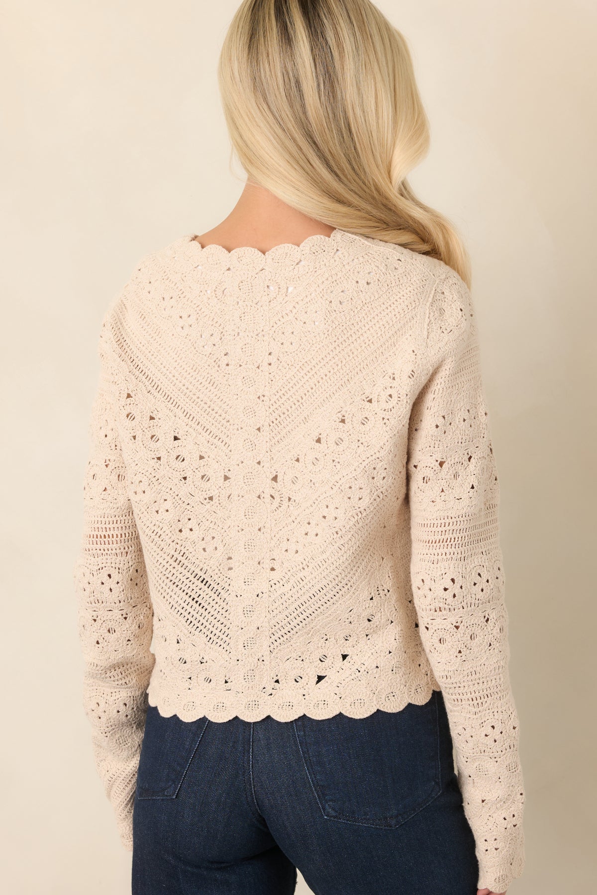 Rear view of the textured crochet cardigan highlighting its dimensional stitchwork, slightly cropped silhouette, and scalloped hem.