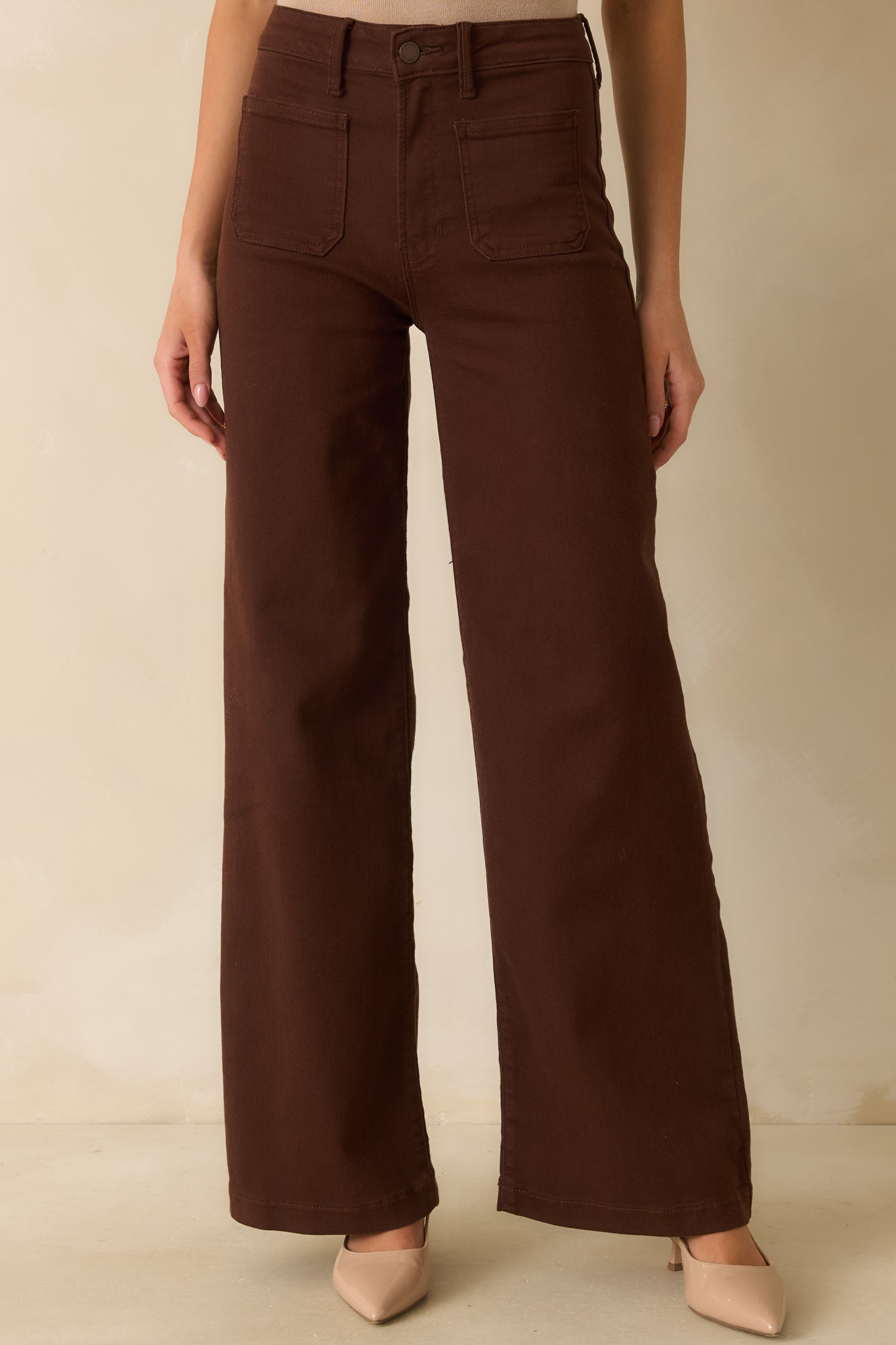 Textured fabric and stitching of the brown jeans highlighting the functional front pockets.