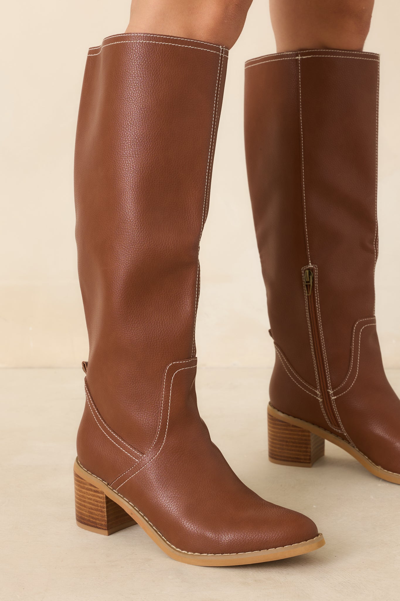 Textured faux leather knee-high boots featuring a streamlined shaft, softly rounded almond toe, and curved contrast stitching for a refined finish.