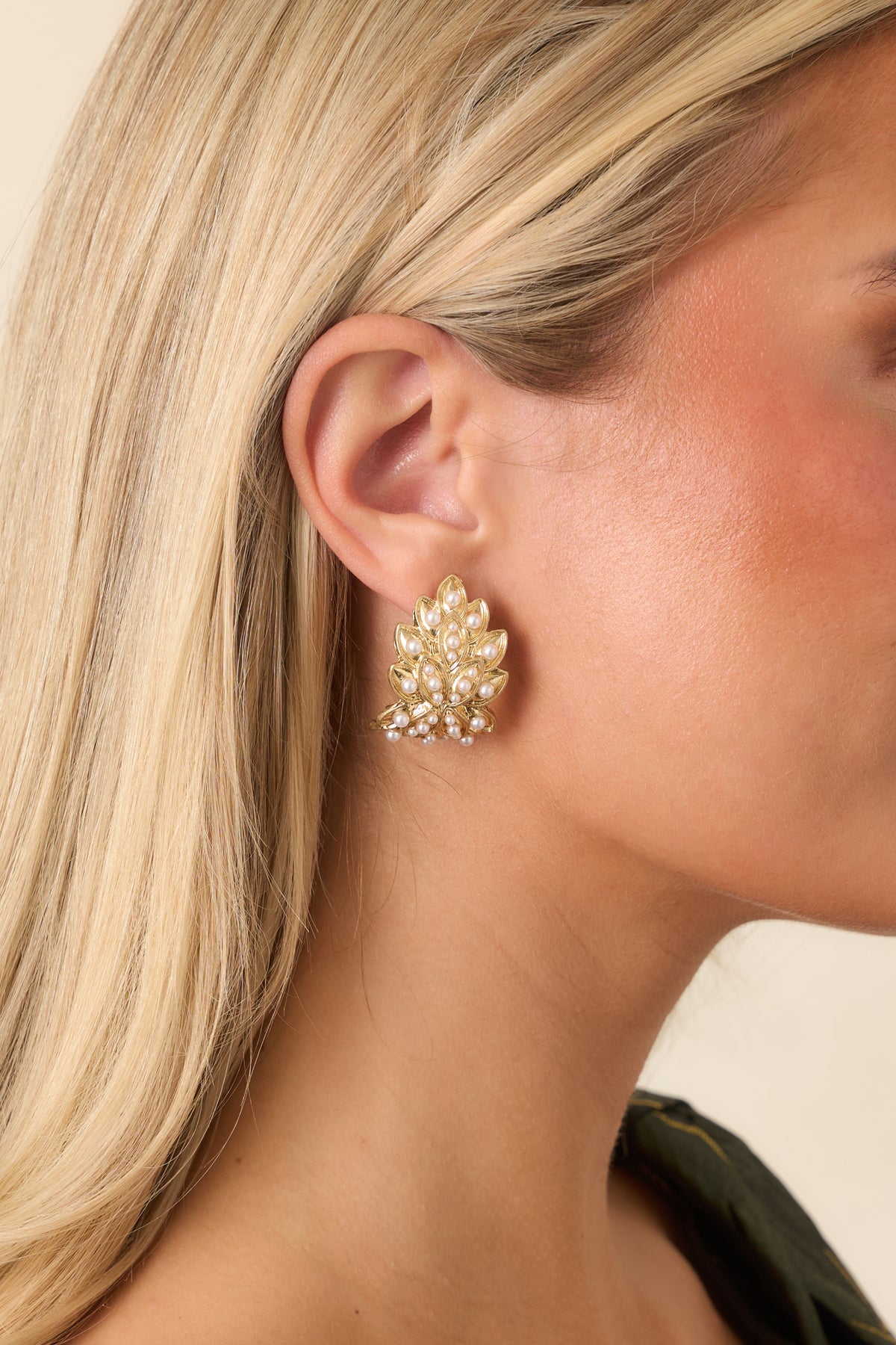 Textured gold earrings featuring a sculptural leaf design decorated with ivory pearl accents