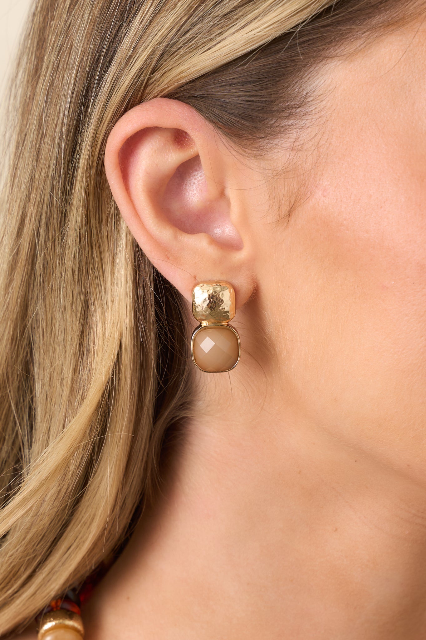 Gold square stud earrings featuring a textured square top, taupe bezel-set gemstone, and secure post backings.