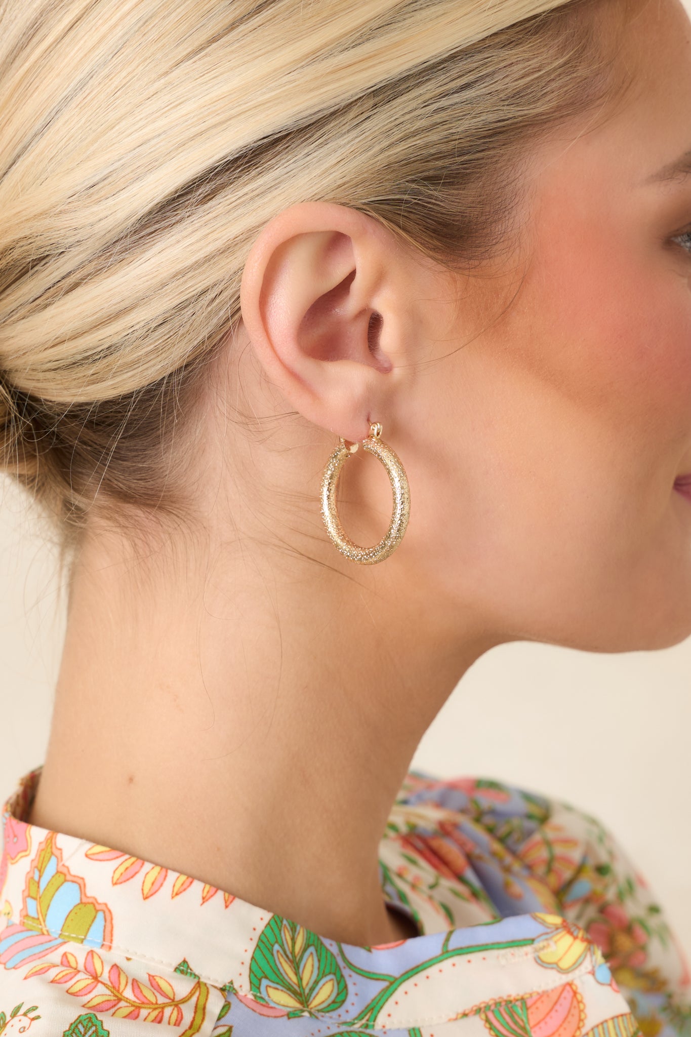 Softly textured gold-tone hoop earrings with a rounded silhouette and subtle light-catching finish.