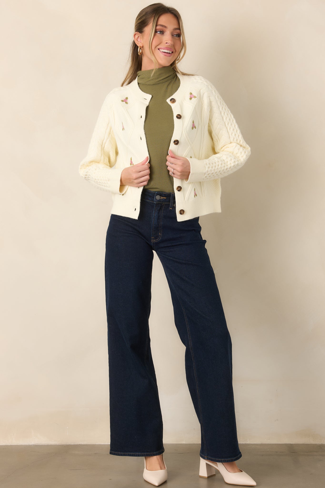 Textured knit cardigan featuring cable-knit stitching, tiny pink floral embroidery, a round neckline, long sleeves, and tortoise-style buttons.