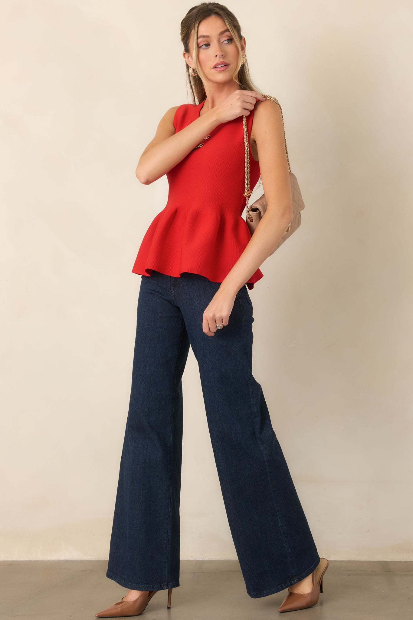 Textured knit top featuring a sleek sleeveless silhouette, fitted waist, gently flared peplum hem, and gold-tone hardware at the neckline.
