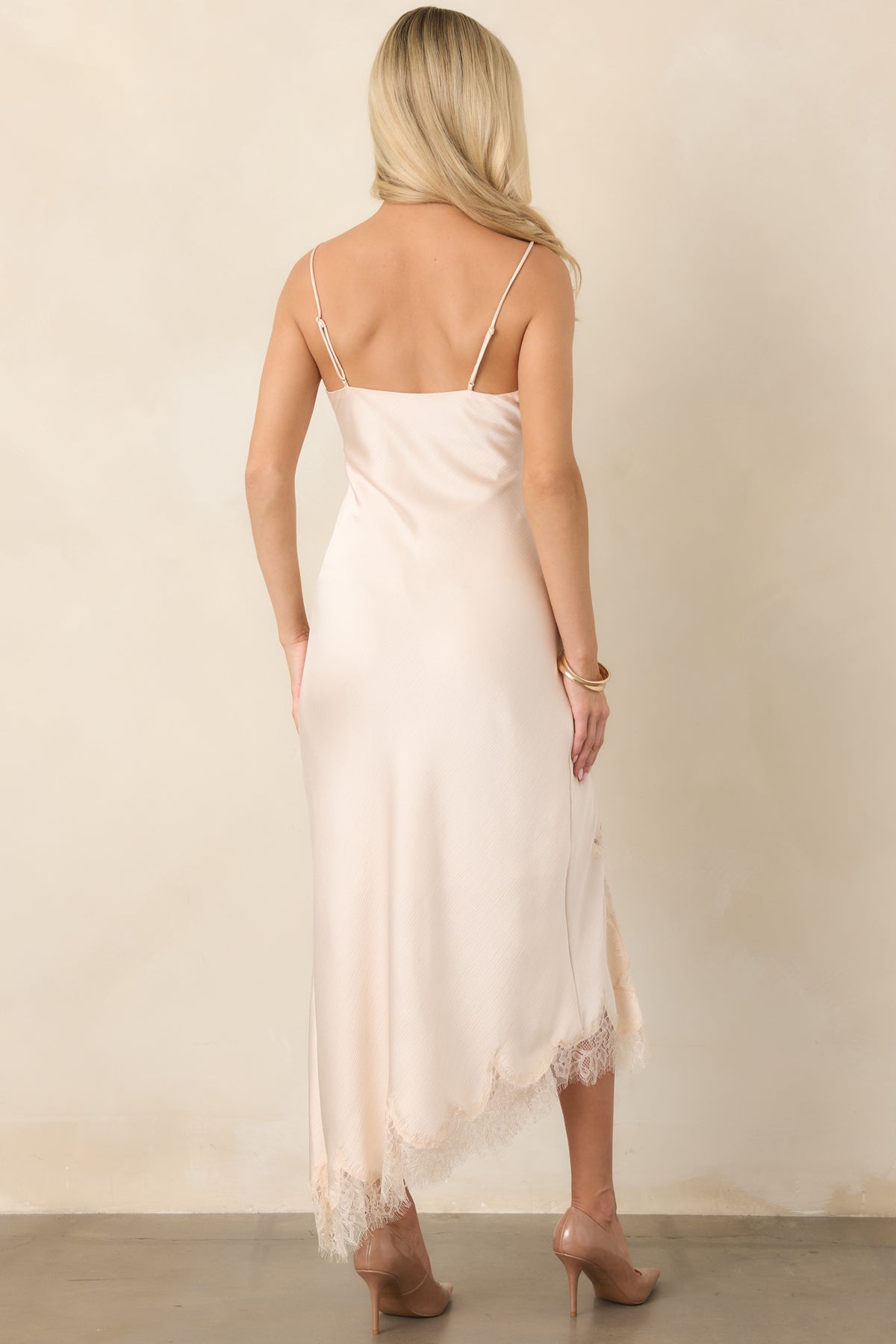 Rear view of the textured satin midi dress showcasing its slender adjustable straps, bias-cut silhouette, and asymmetrical lace-trimmed hem.