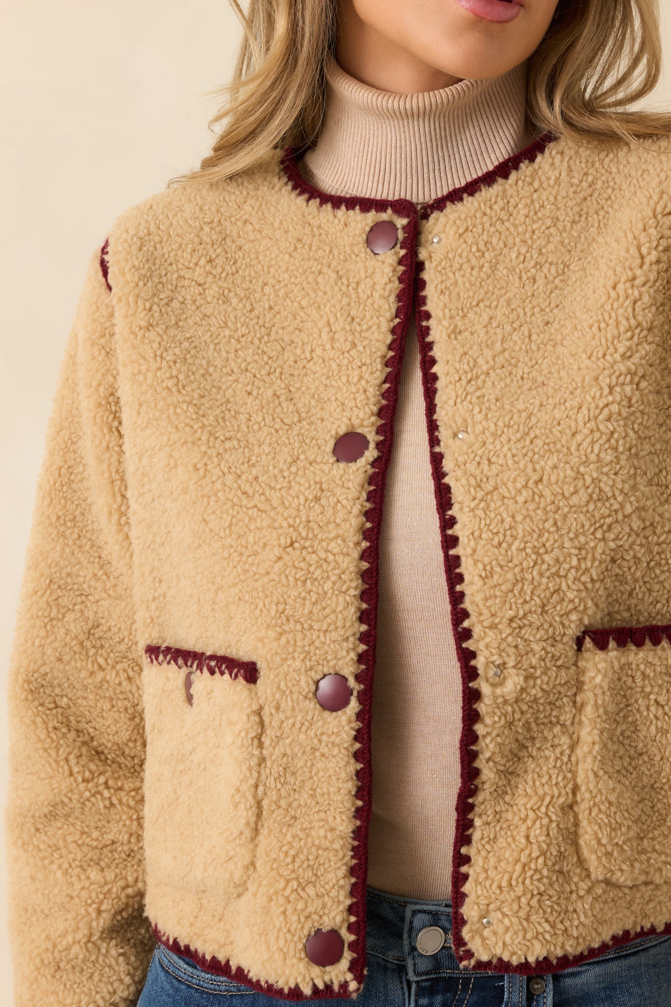 Detailed view of the textured sherpa material and crisp burgundy whipstitch edging.