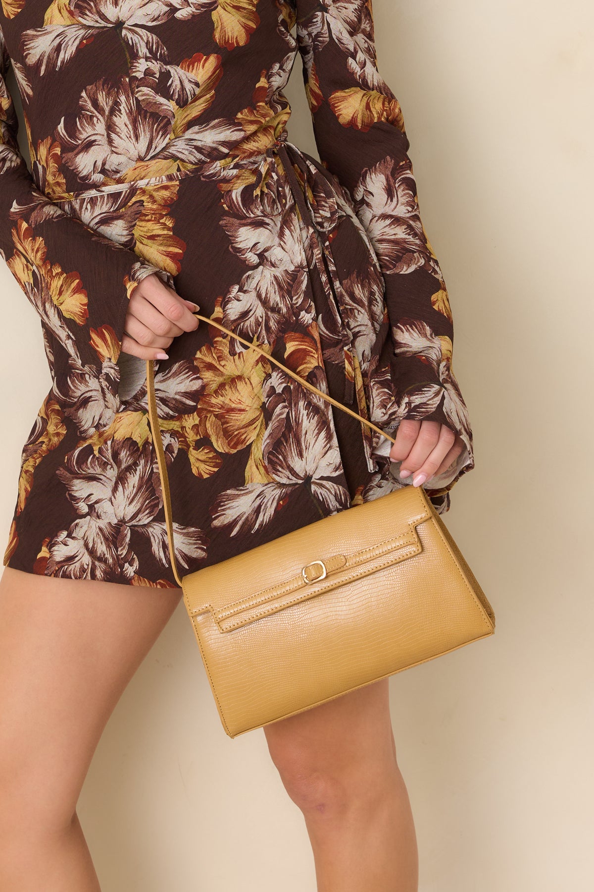 Textured shoulder bag with an envelope-style flap, slim strap, and delicate gold-tone buckle clasp.