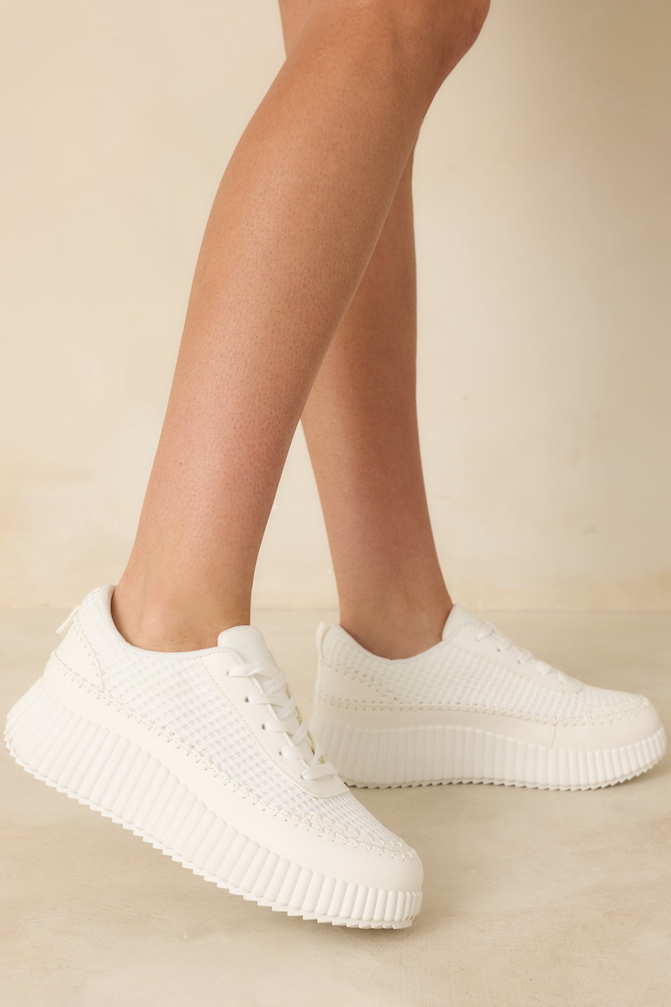 Textured white knit sneakers showing a bold, ridged platform sole with durable traction.