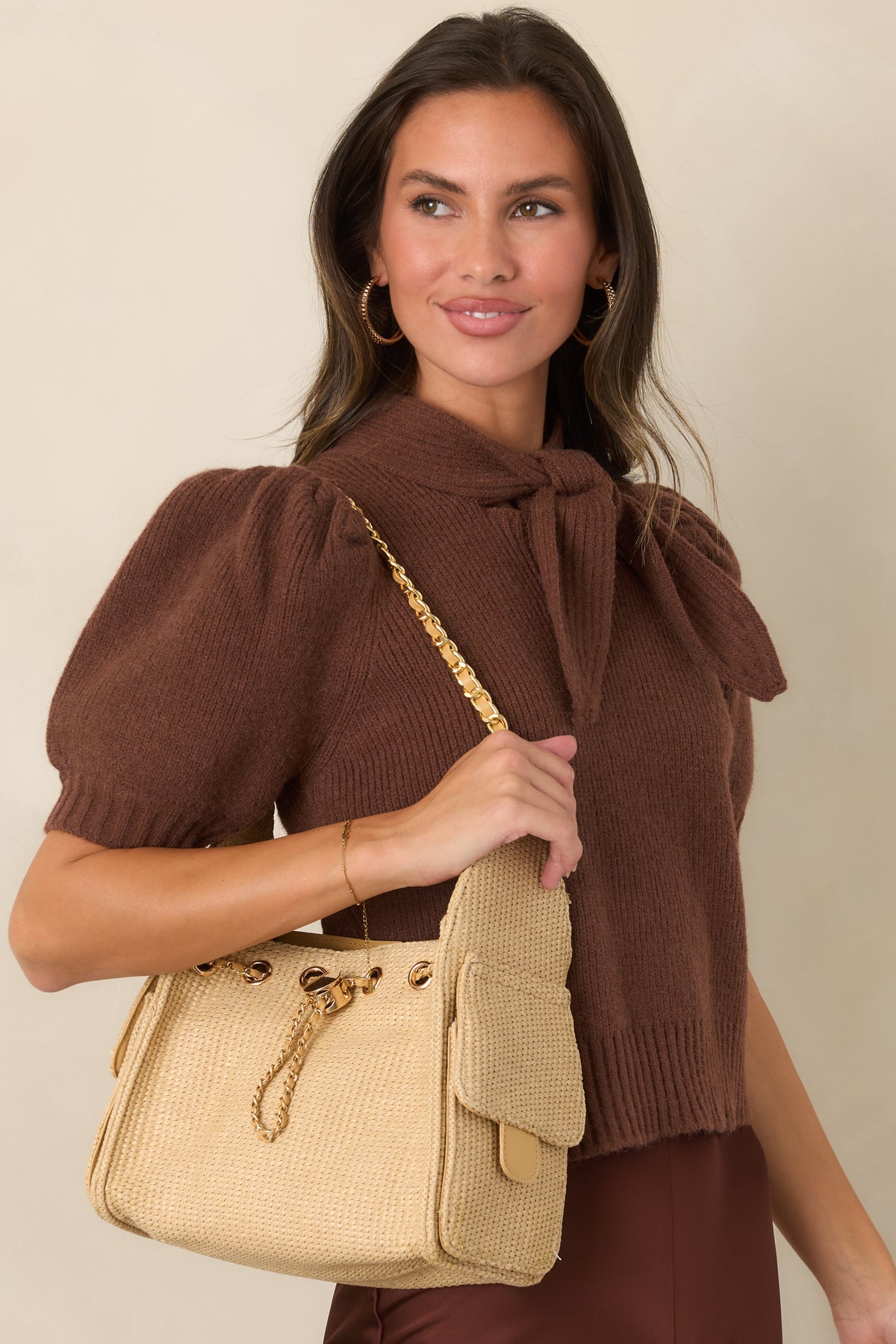 Textured handbag with a natural woven finish, gold-tone accents, adjustable chain strap, and a spacious structured silhouette.