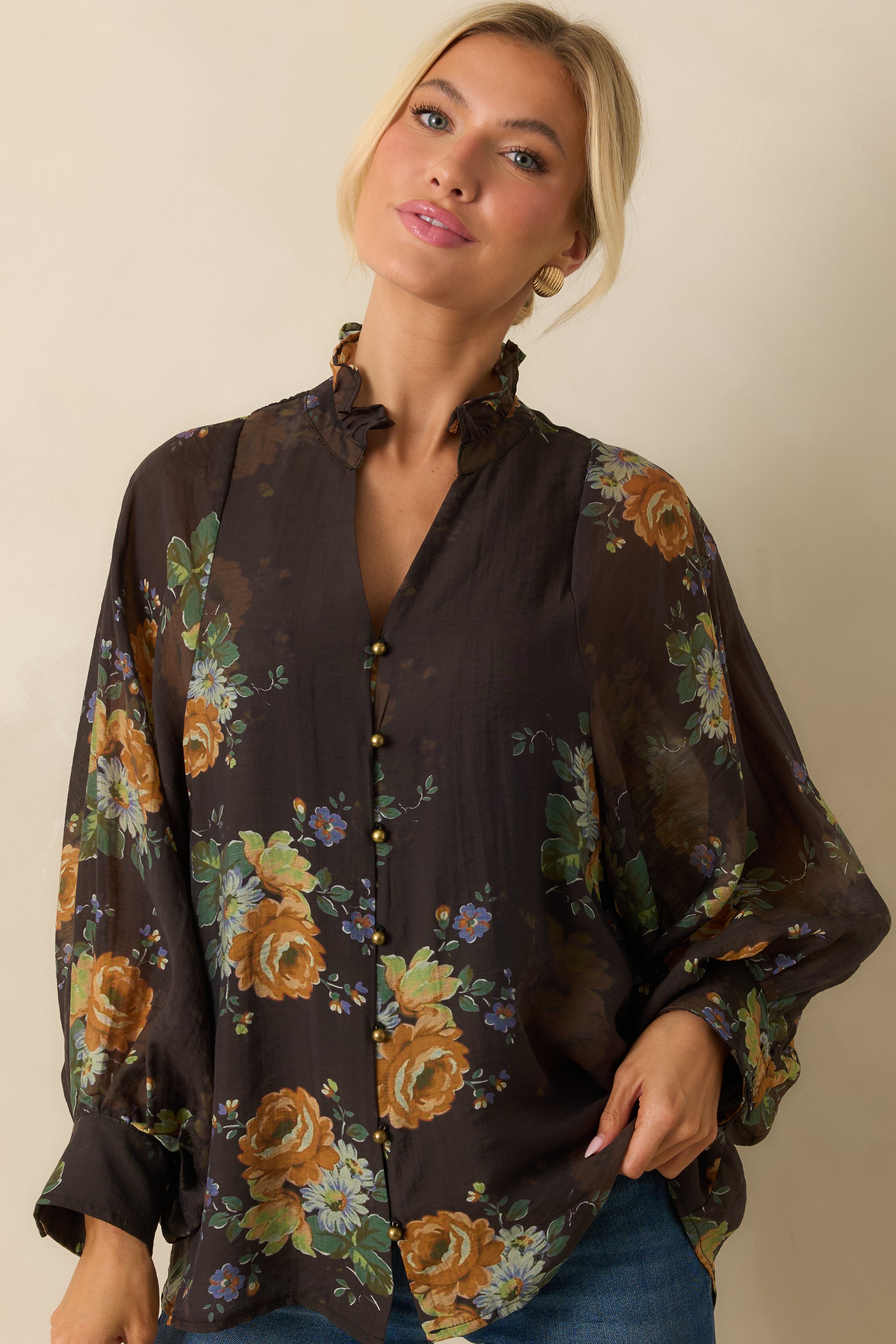 Close-up of the ruffled neckline and gold buttons emphasizing the floral pattern on the blouse.