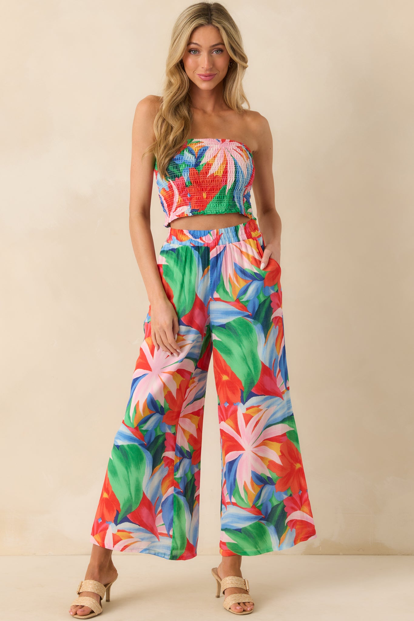 Full body front view showing the strapless smocked top with a pink multicolor tropical floral print and ruffled bottom hem.