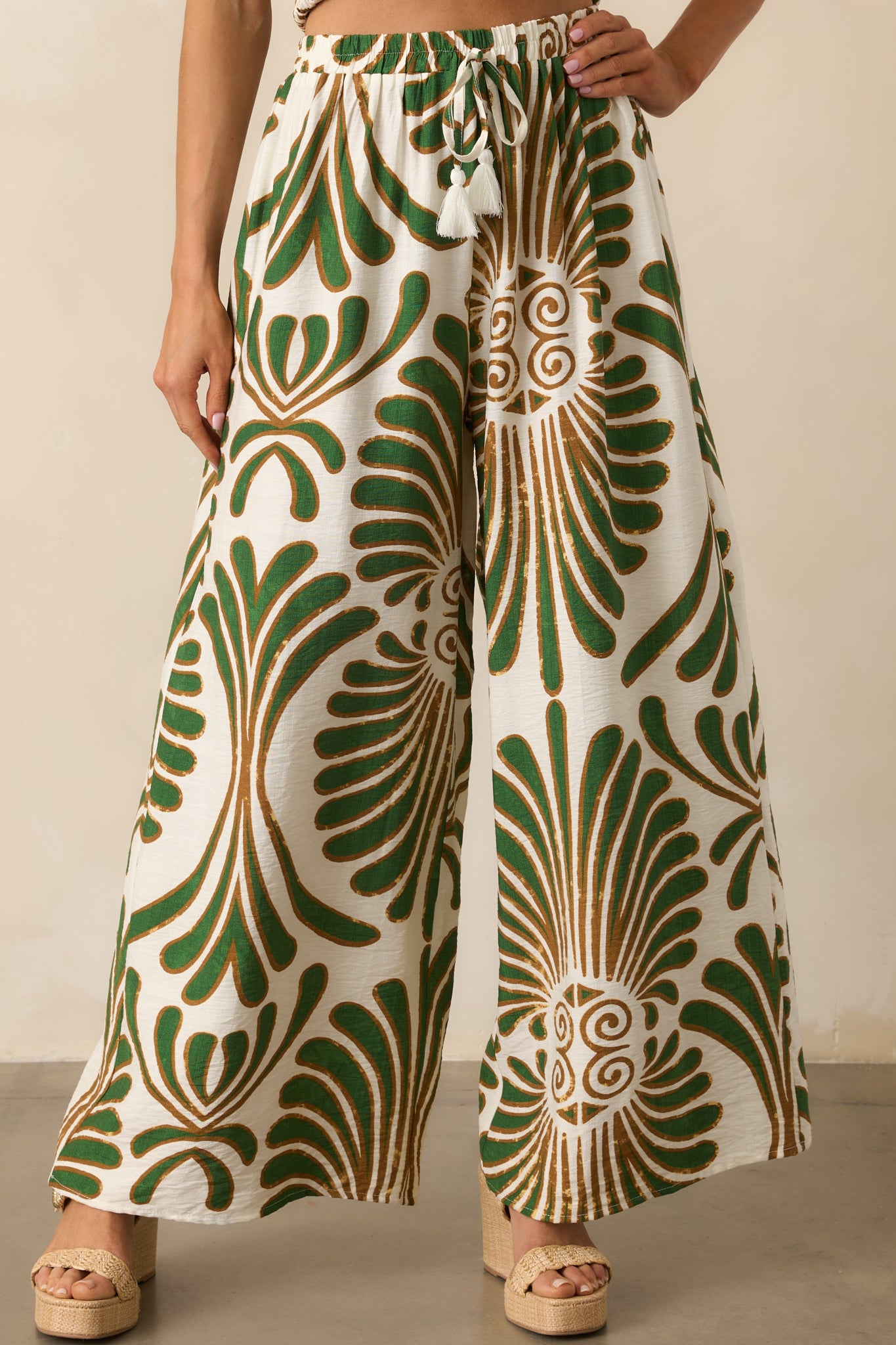 Cropped view of the waistband showing the elastic detail, drawstring ties, and ivory fringe tassels.