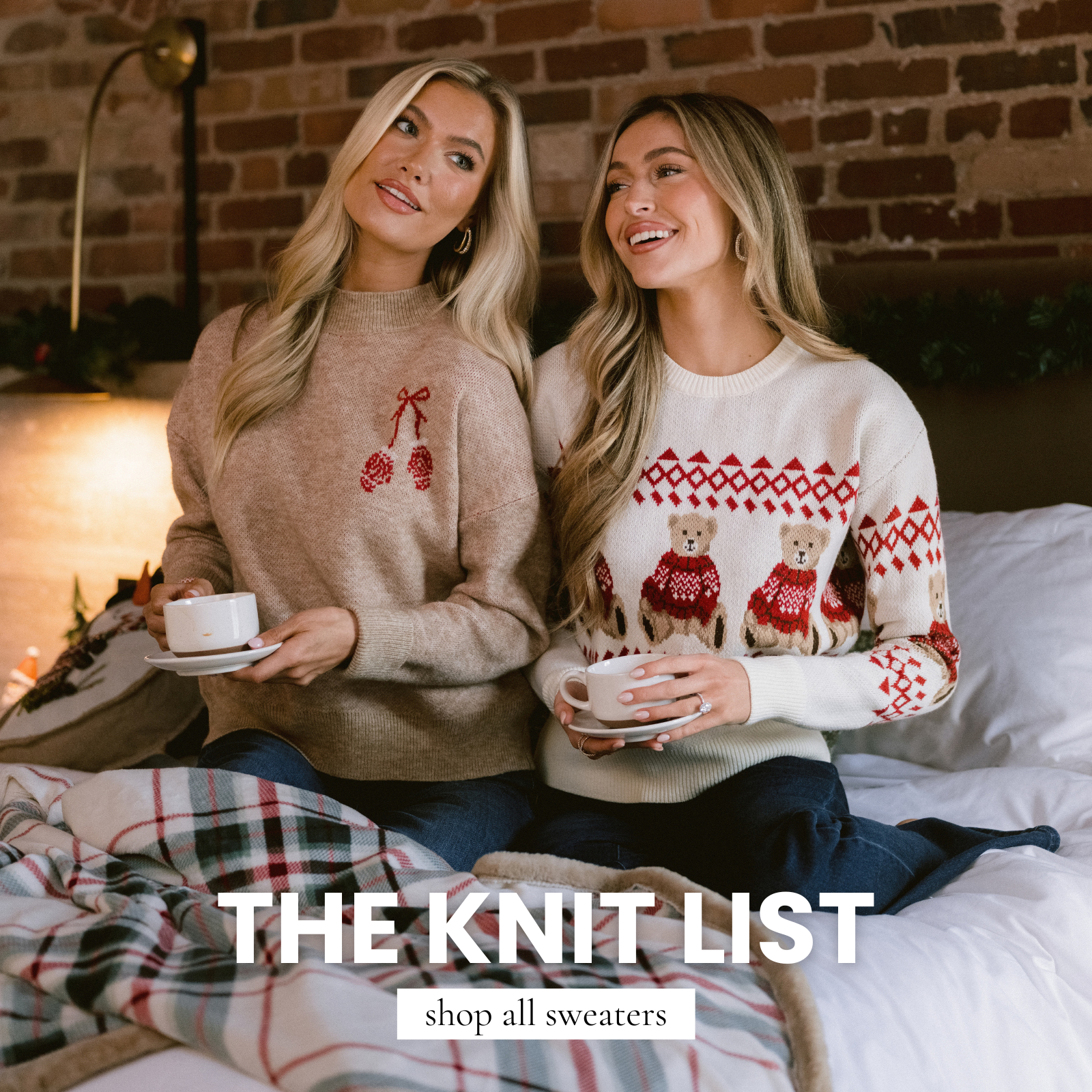 Two models wearing cozy holiday knit sweaters—one tan pinecone sweater and one ivory teddy bear fair-isle sweater—sitting on a bed as a banner linking to our women’s All Sweaters collection.
