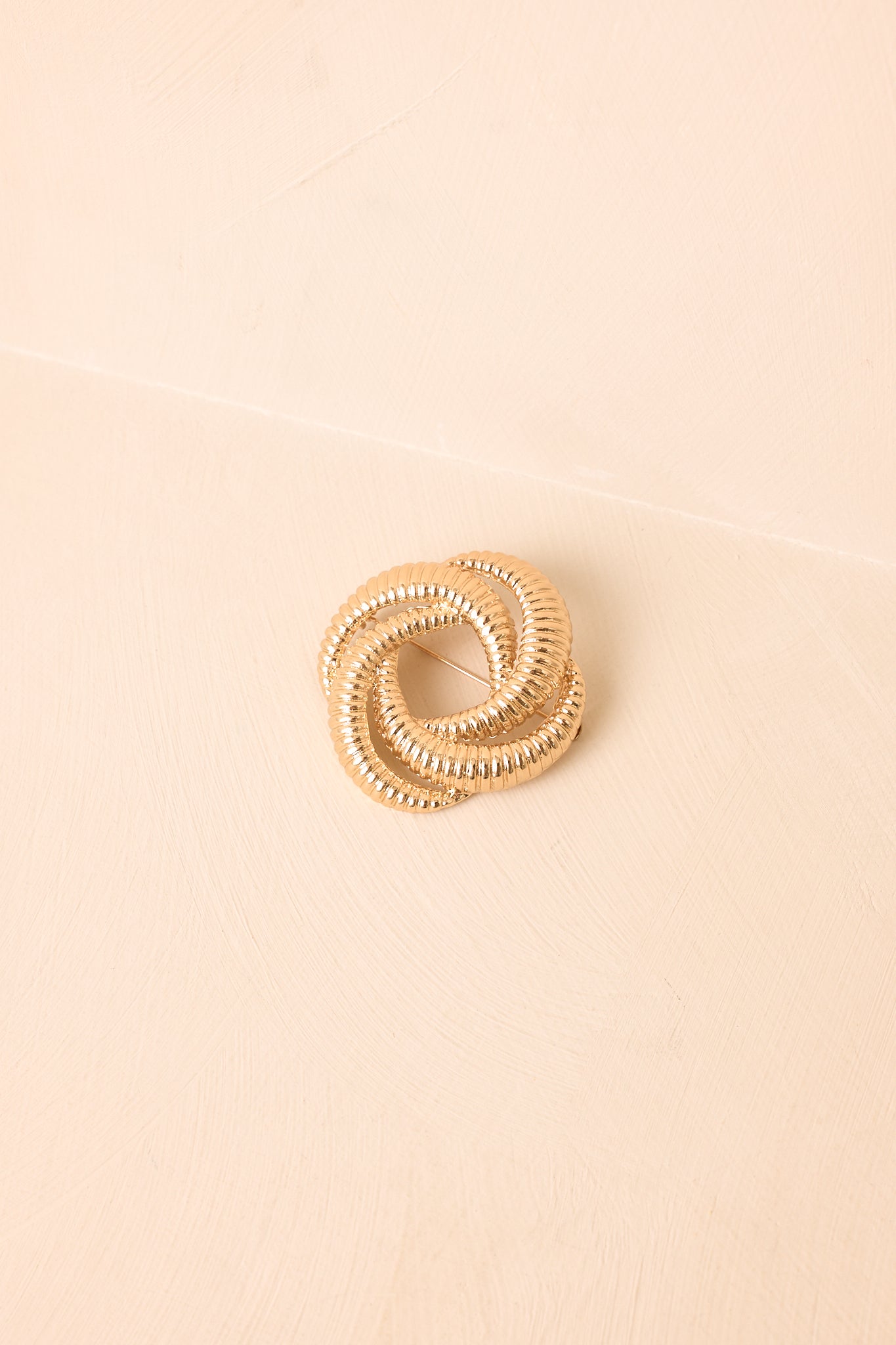 Close view of the brooch highlighting the three connected loops, dimensional knot construction, and detailed ribbed texture.