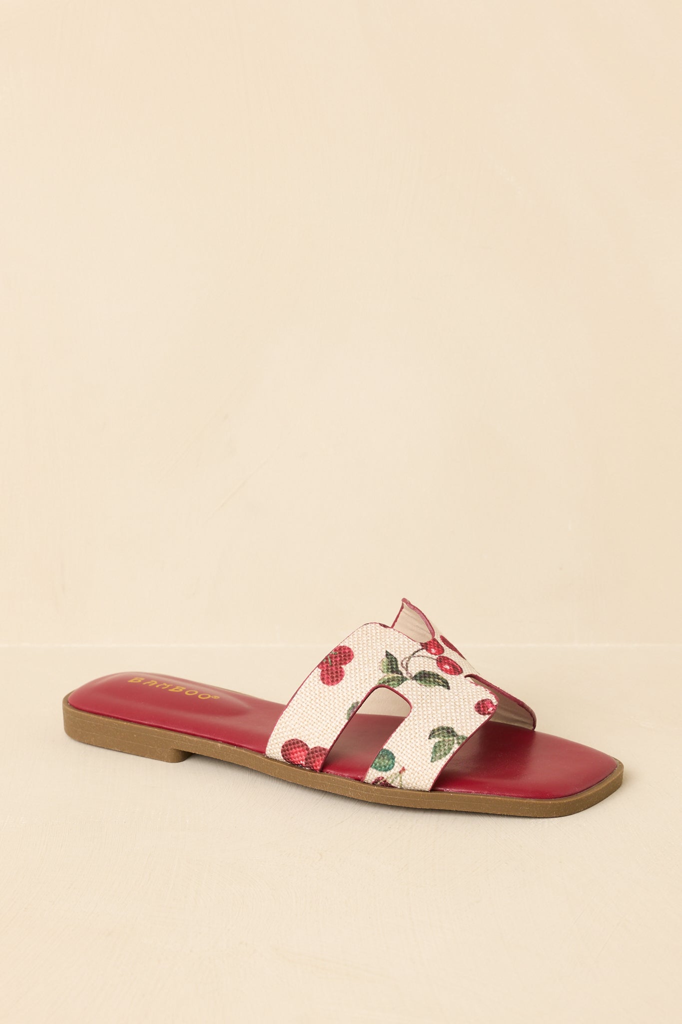Three-quarter angle of fruit print slide sandals on beige background emphasizing lightweight construction