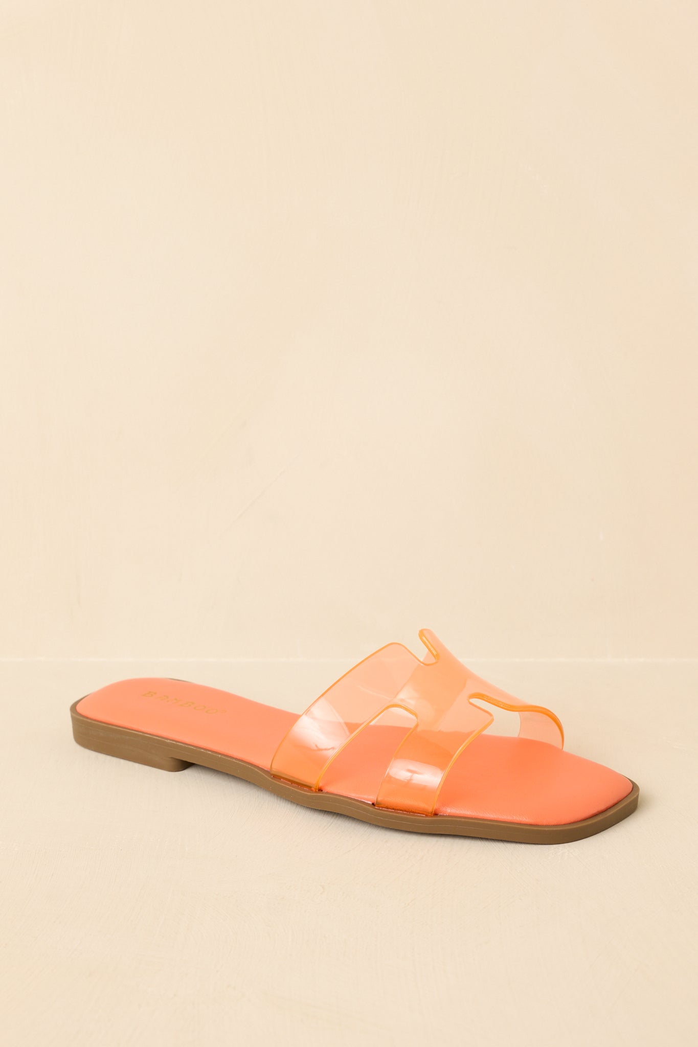 Three-quarter angle showcasing the transparency of the vinyl strap and the smooth curve of the footbed.