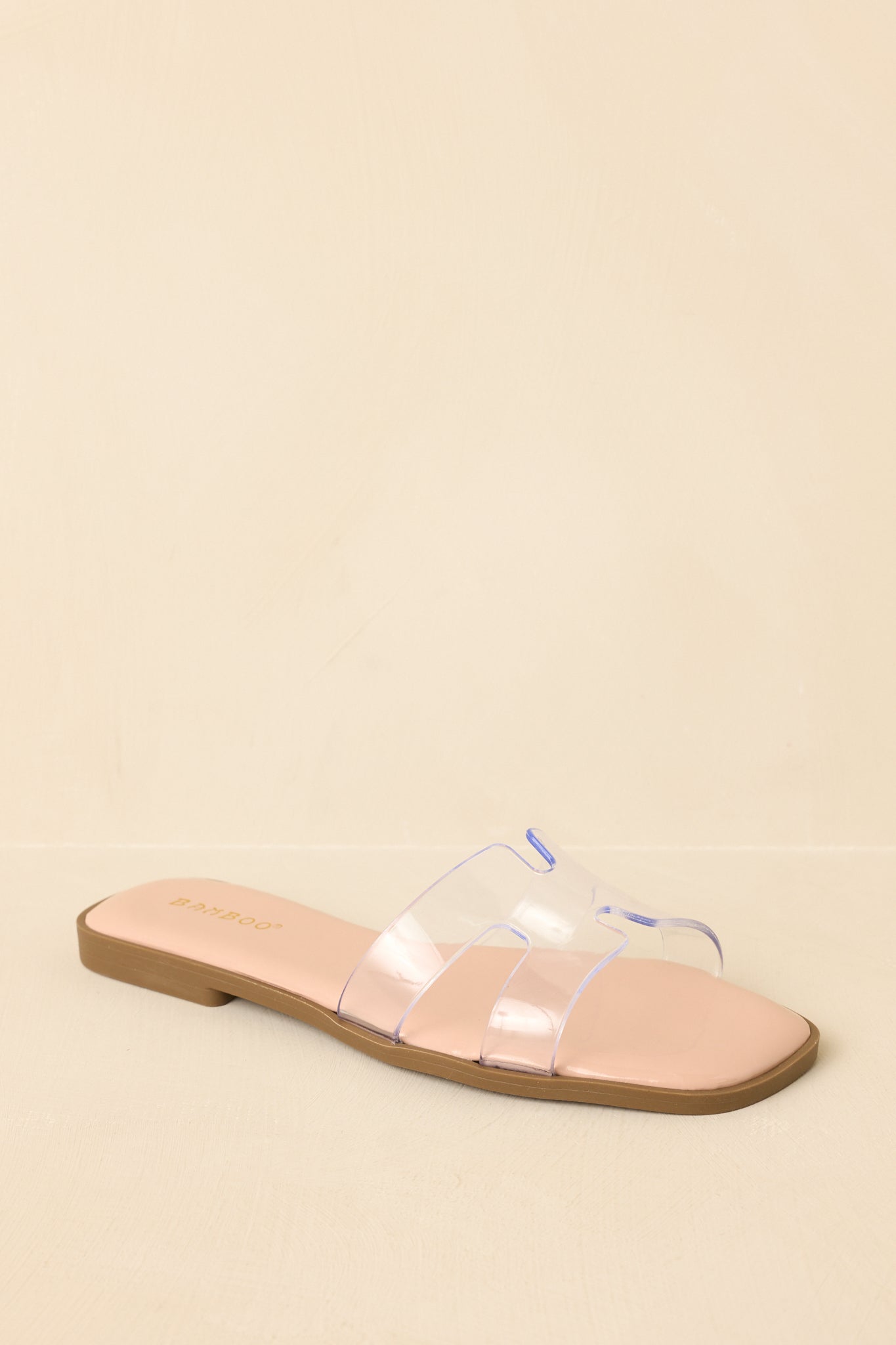 Three-quarter angle showcasing transparent strap and neutral footbed design.