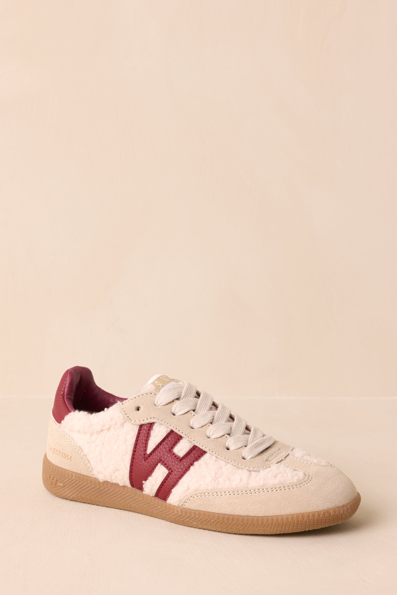 Three-quarter side view emphasizing layered panel design, side logo patch, and flat brown rubber outsole.