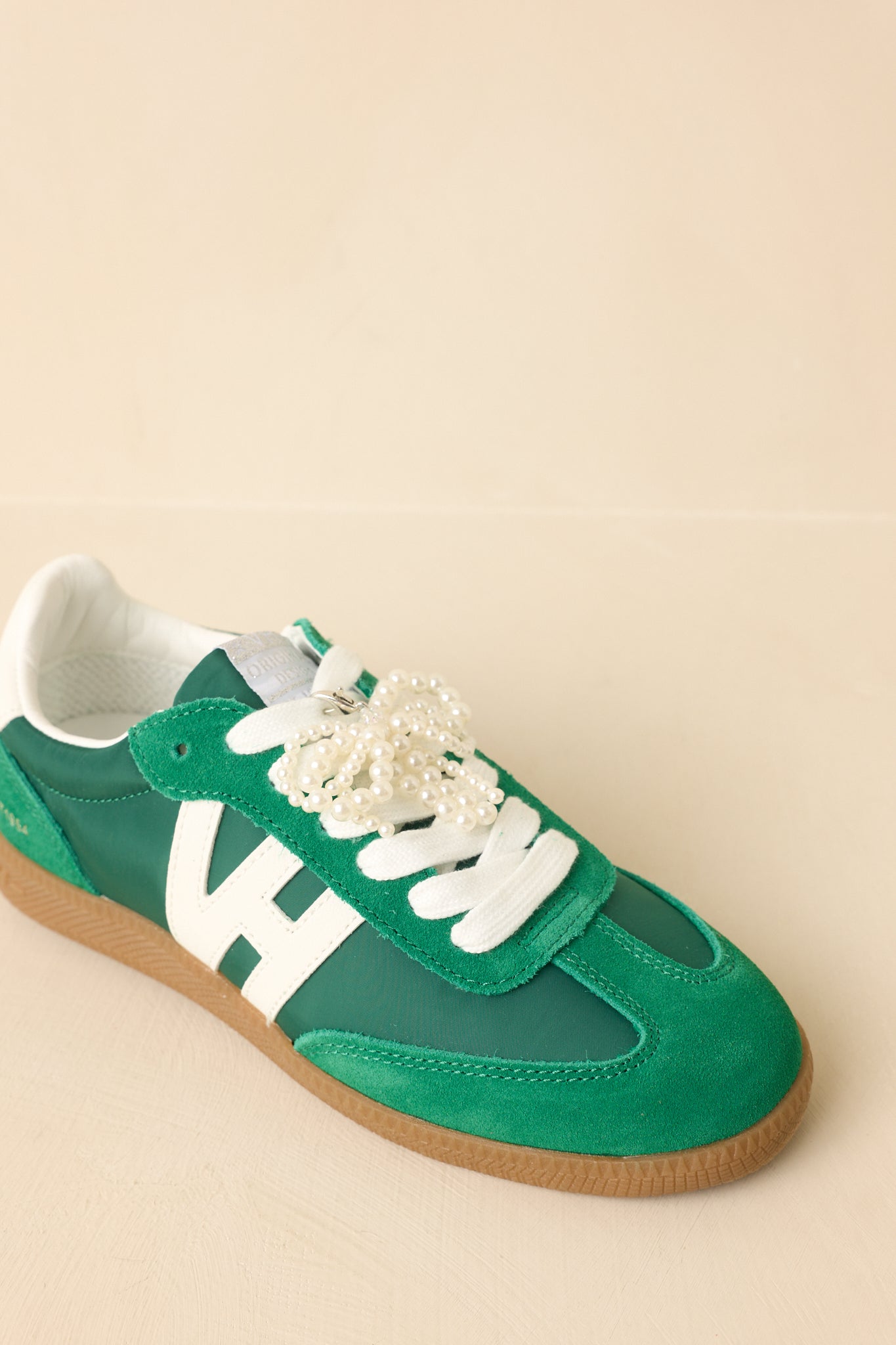 Beige background three-quarter view emphasizing the dimensional mix of materials and structured sneaker shape.