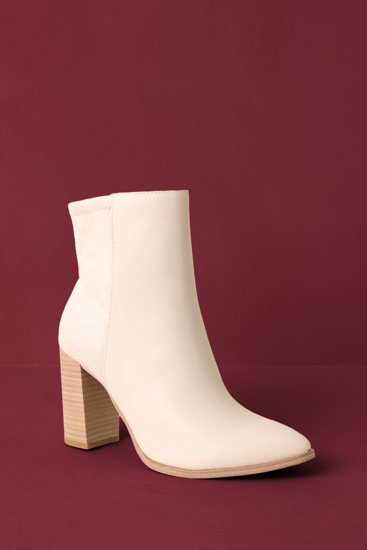 Boots angled to highlight the outer seam detail and inner zipper closure on burgundy back drop.