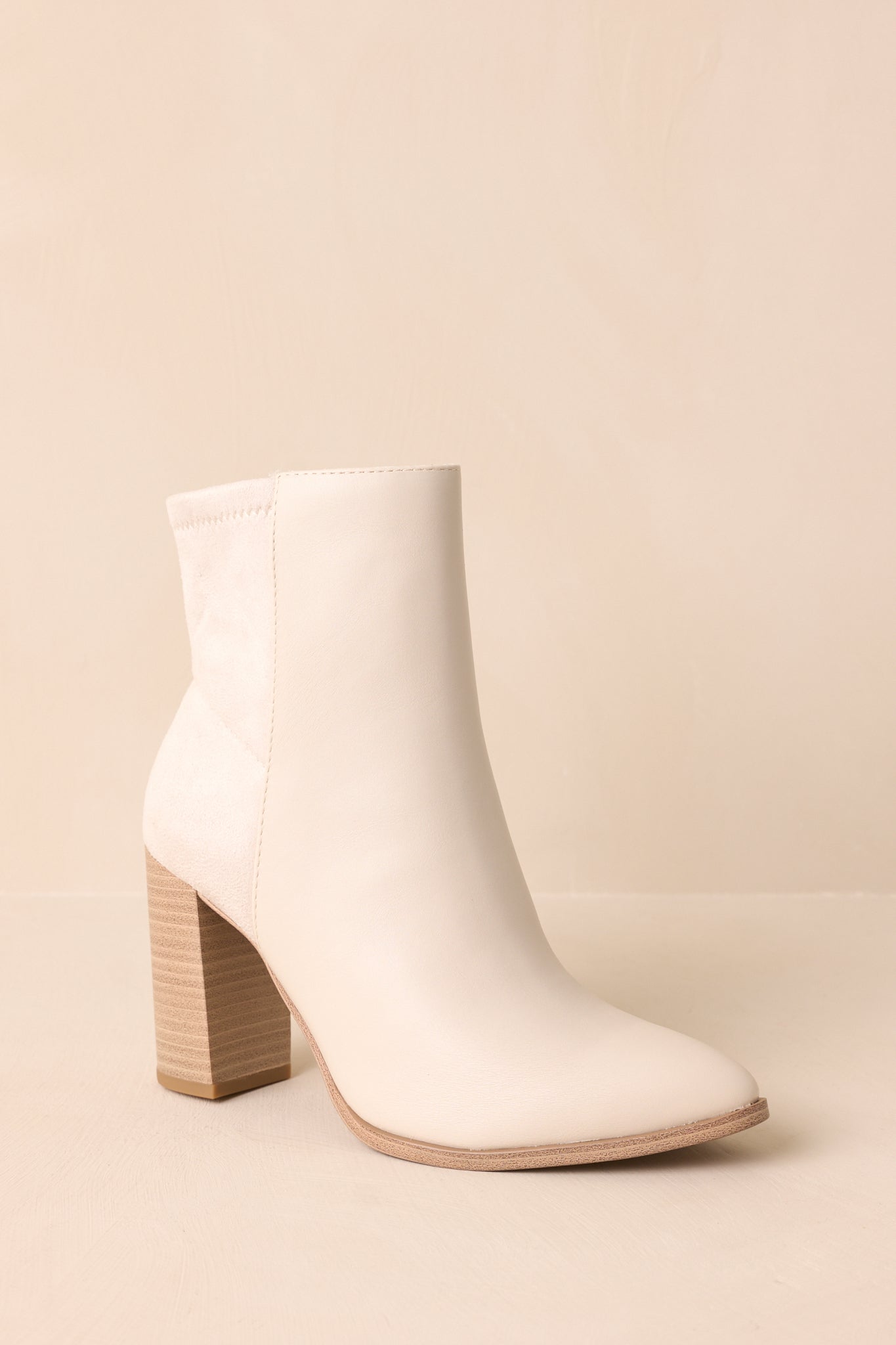 Three-quarter view of the ankle boots featuring tonal faux suede accents and a polished ivory finish.