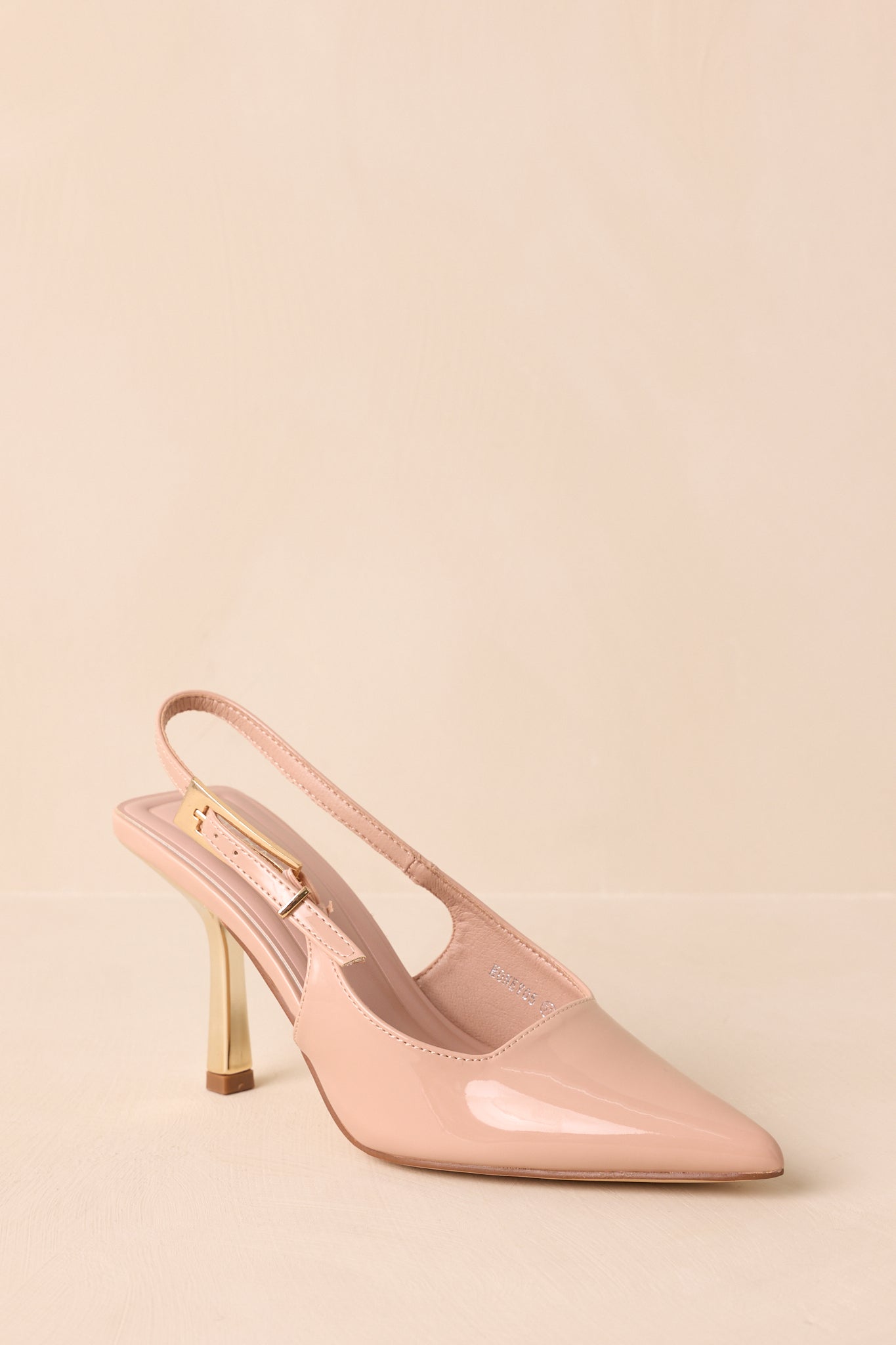 Three-quarter view of beige heels showing gold accents and slingback design.