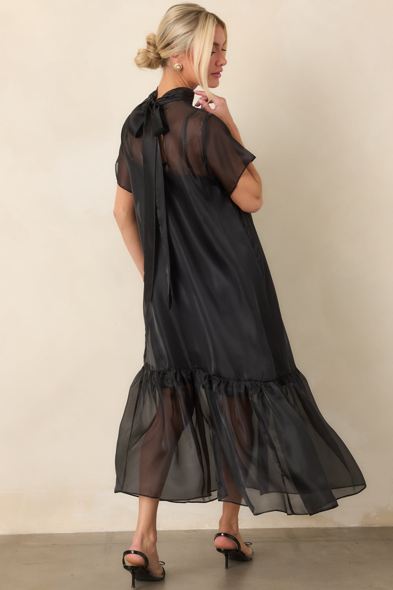 Rear view of the sheer organza maxi dress showing the elegant tie-back neckline, layered slip lining, and gathered ruffle hem.