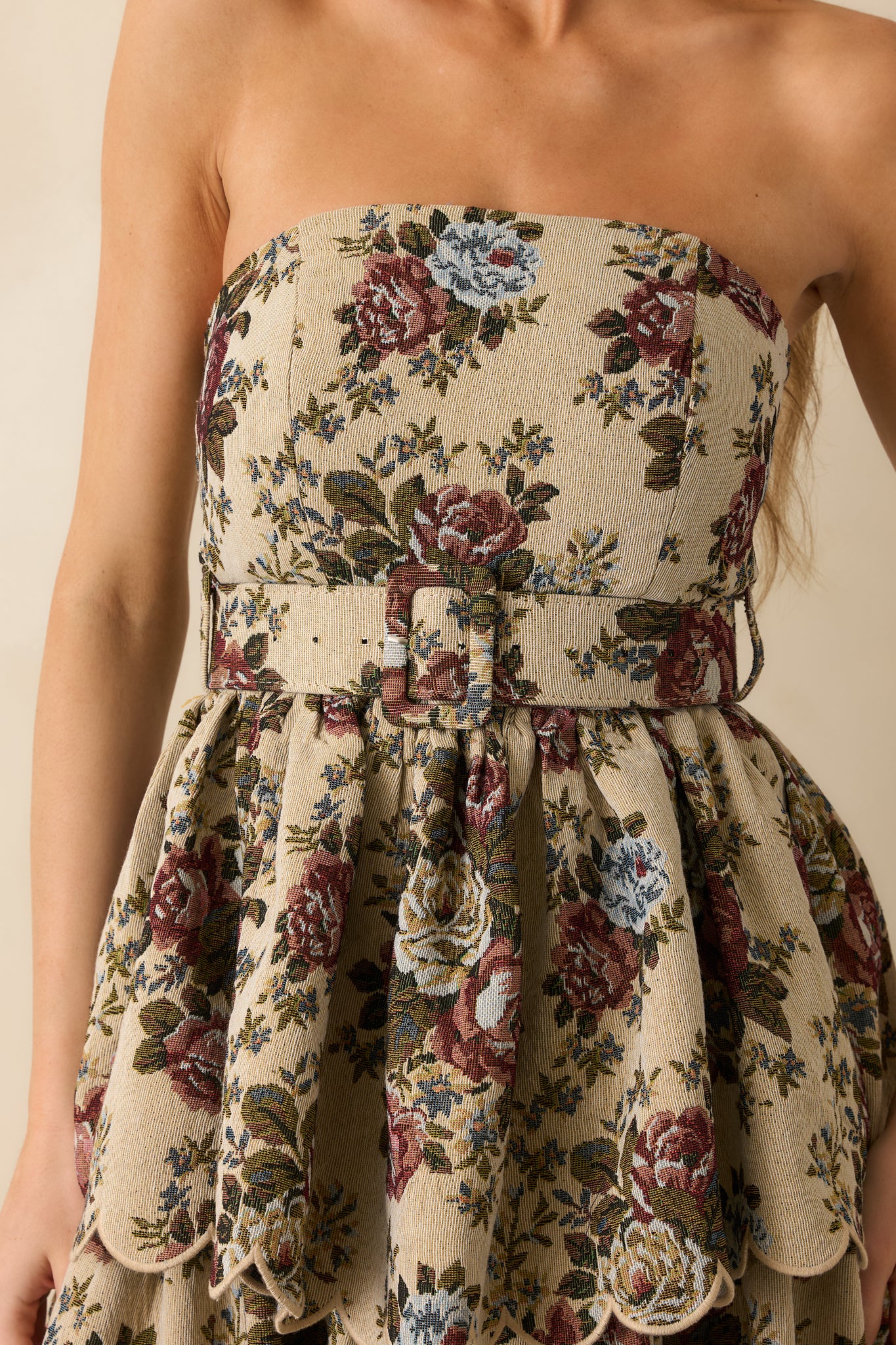 Tight shot of the dress’ fabric showing floral tapestry pattern, textured material, and scalloped tier edges.
