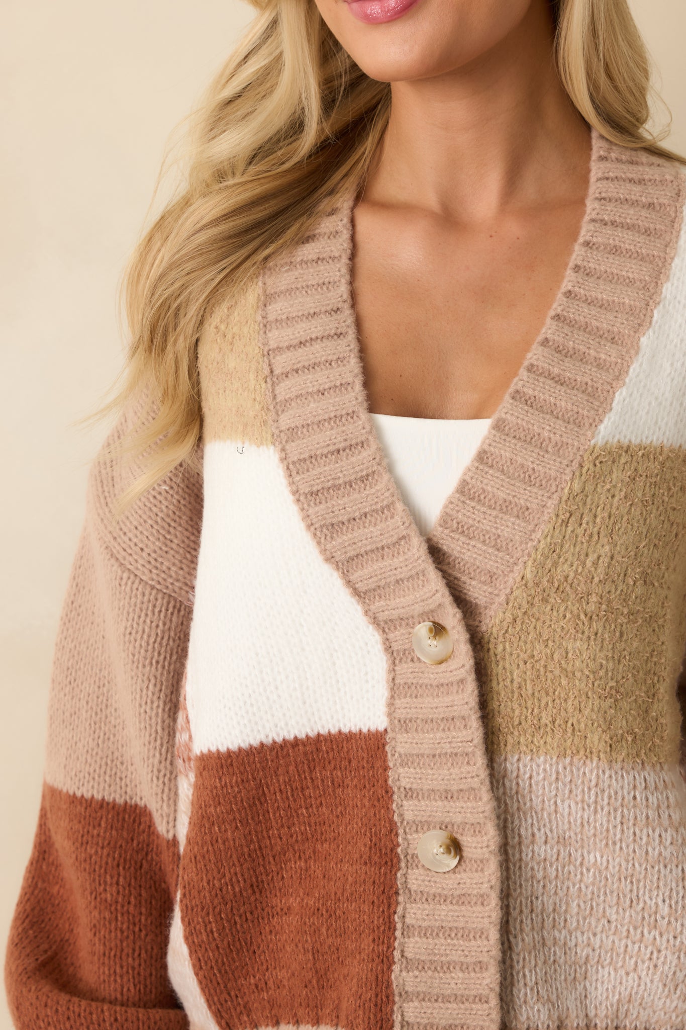 Tight shot of taupe knit fabric showing color block texture and button closure details.