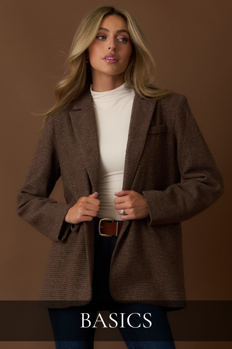 Model wearing a brown plaid blazer over a cream turtleneck top and dark jeans, styled with a leather belt. Showcasing effortless layering and classic wardrobe staples from Red Dress's Basics Collection — timeless pieces designed for everyday wear and elevated fall fashion.