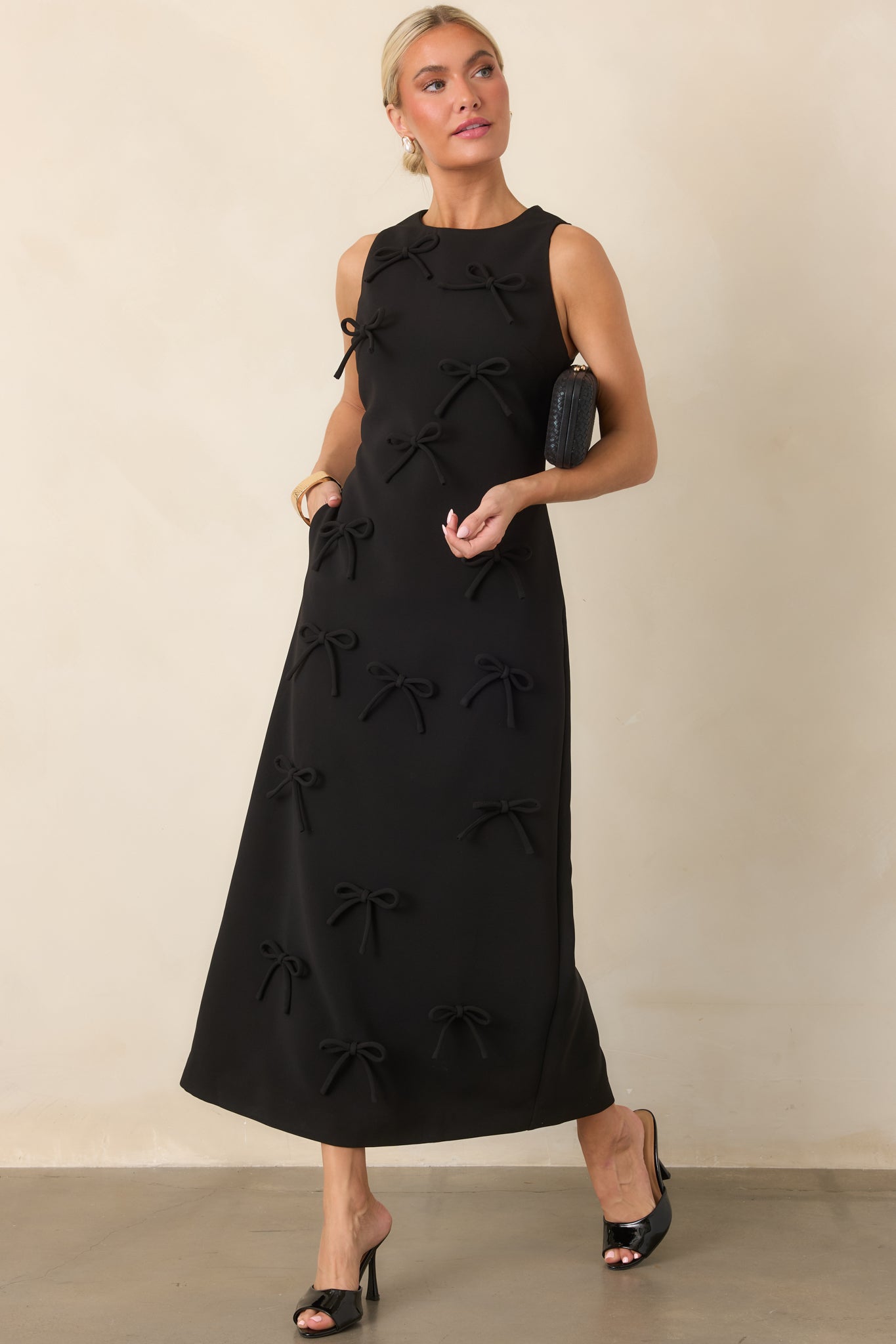 Sleeveless maxi dress featuring a clean round neckline, fitted column silhouette, and tonal three-dimensional bows throughout.