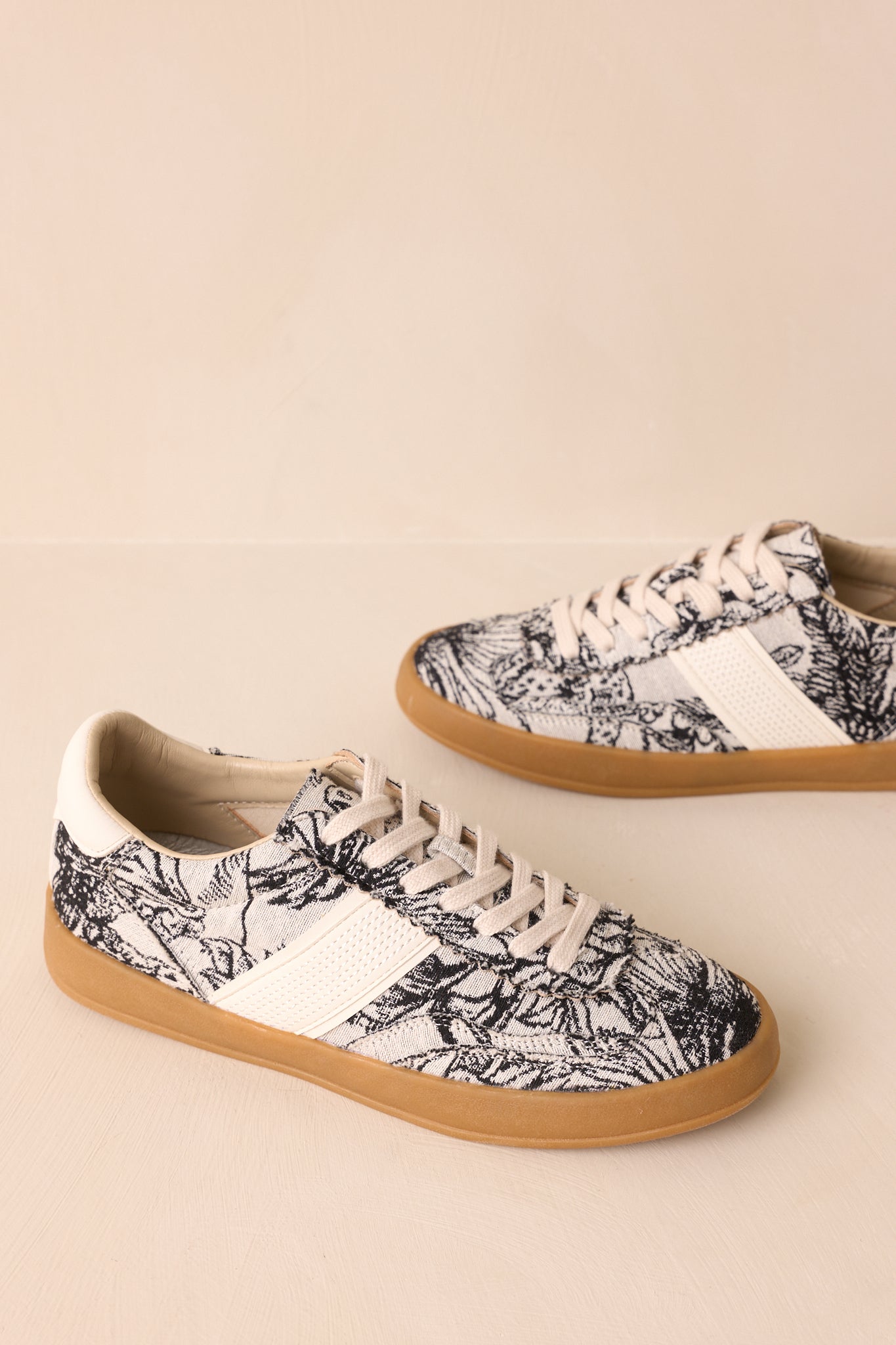 Top-down angle emphasizing the laces, floral print, and structured cream faux leather panels.